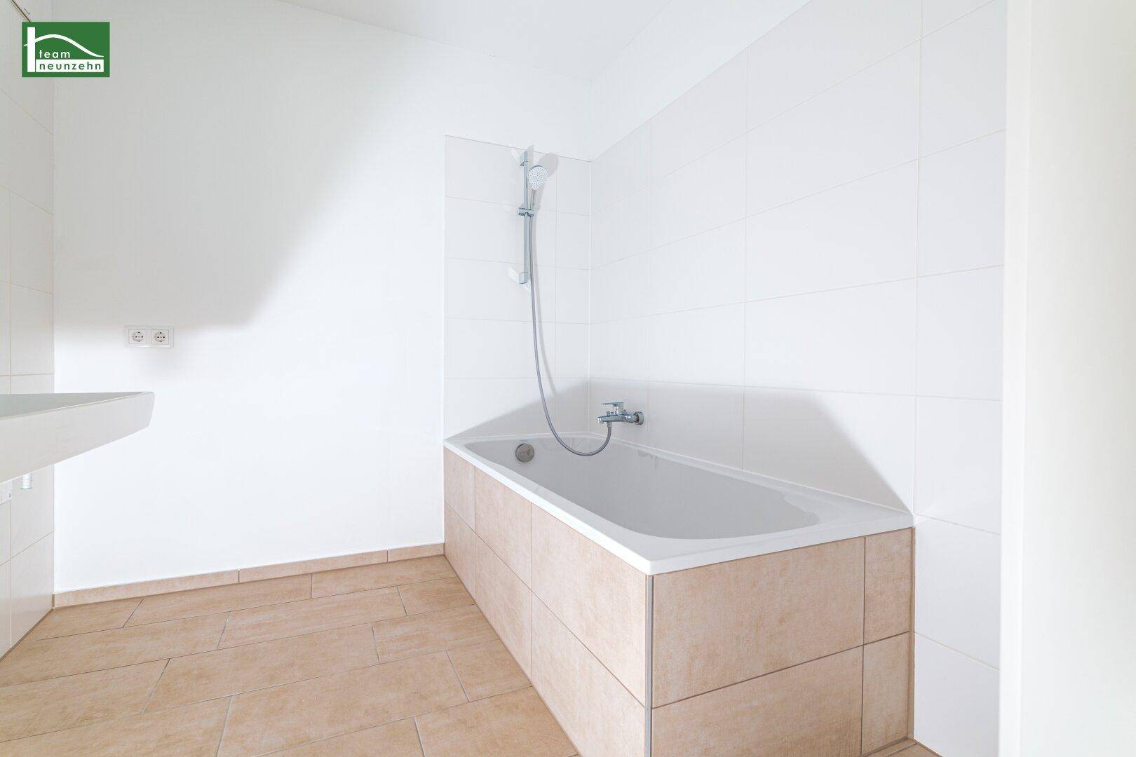 Helles Badezimmer mit Badewanne und weiß gefliesten Wänden, bereit zur Nutzung.