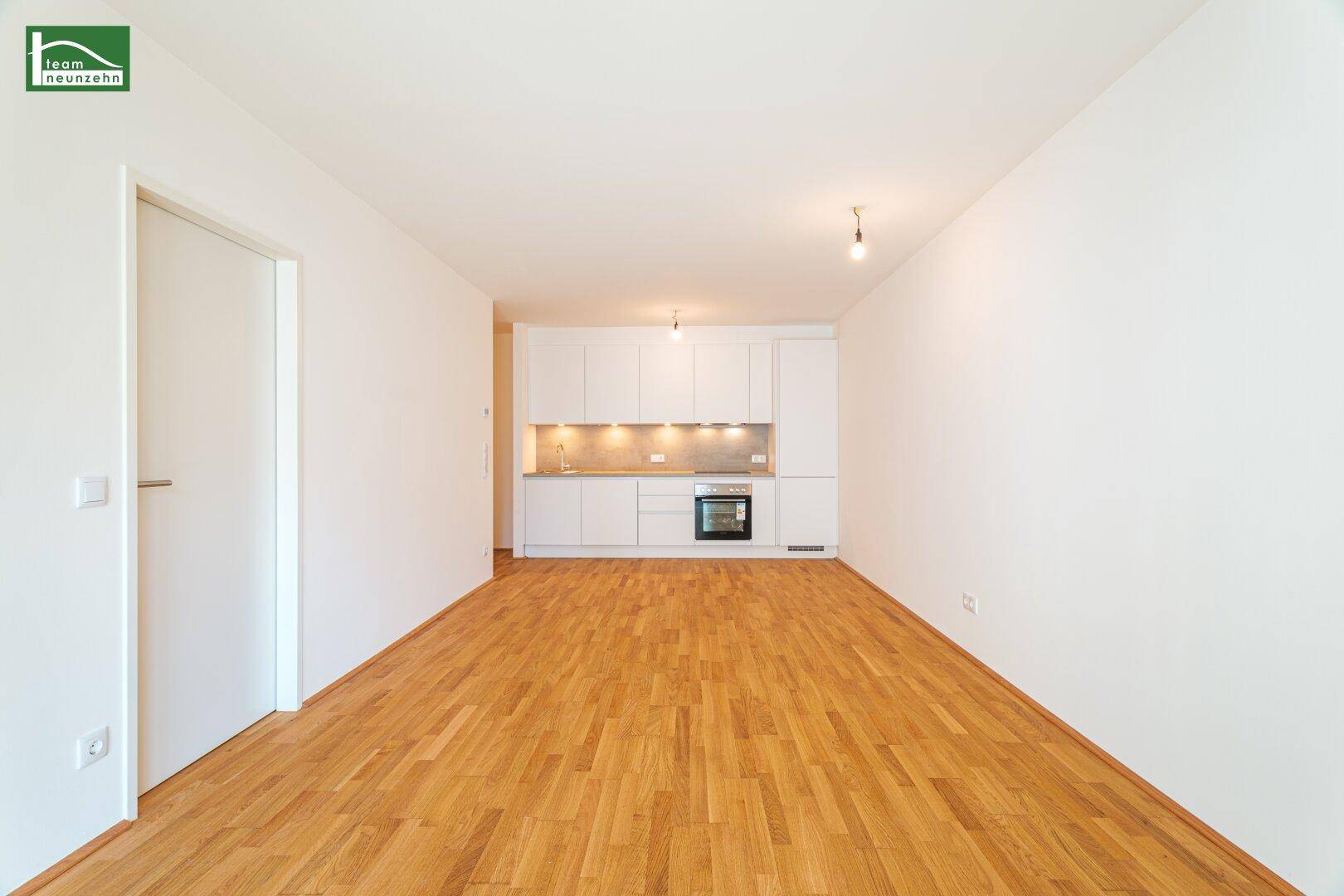 Heller Wohnbereich mit Parkettboden und integrierter Küchenzeile in modernem Design.