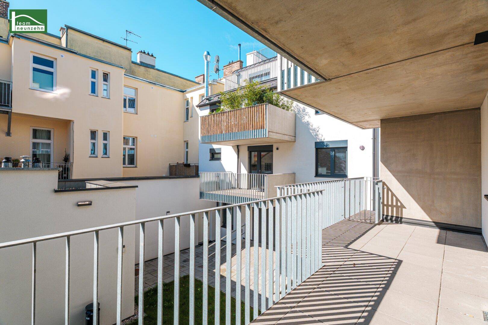 Sonniger Terrassenbereich mit Blick auf die umliegenden Wohngebäude und Grünflächen.