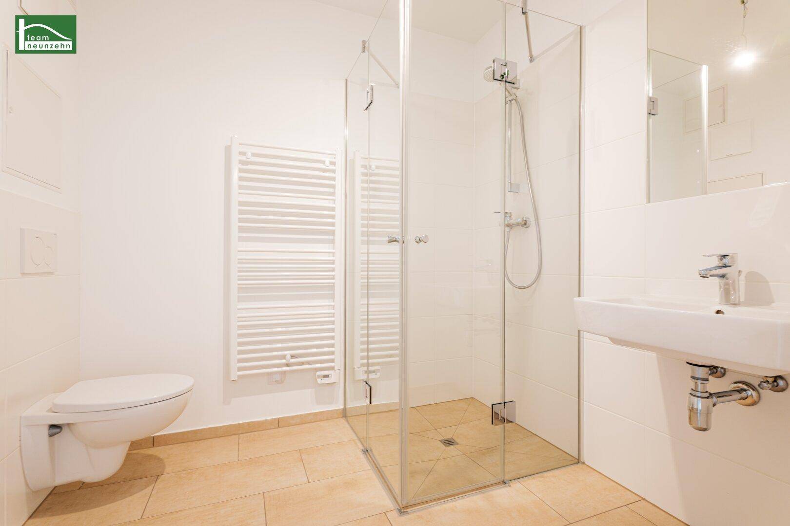 Modernes Badezimmer mit ebenerdiger Dusche, wandhängendem WC und Handtuchheizkörper.