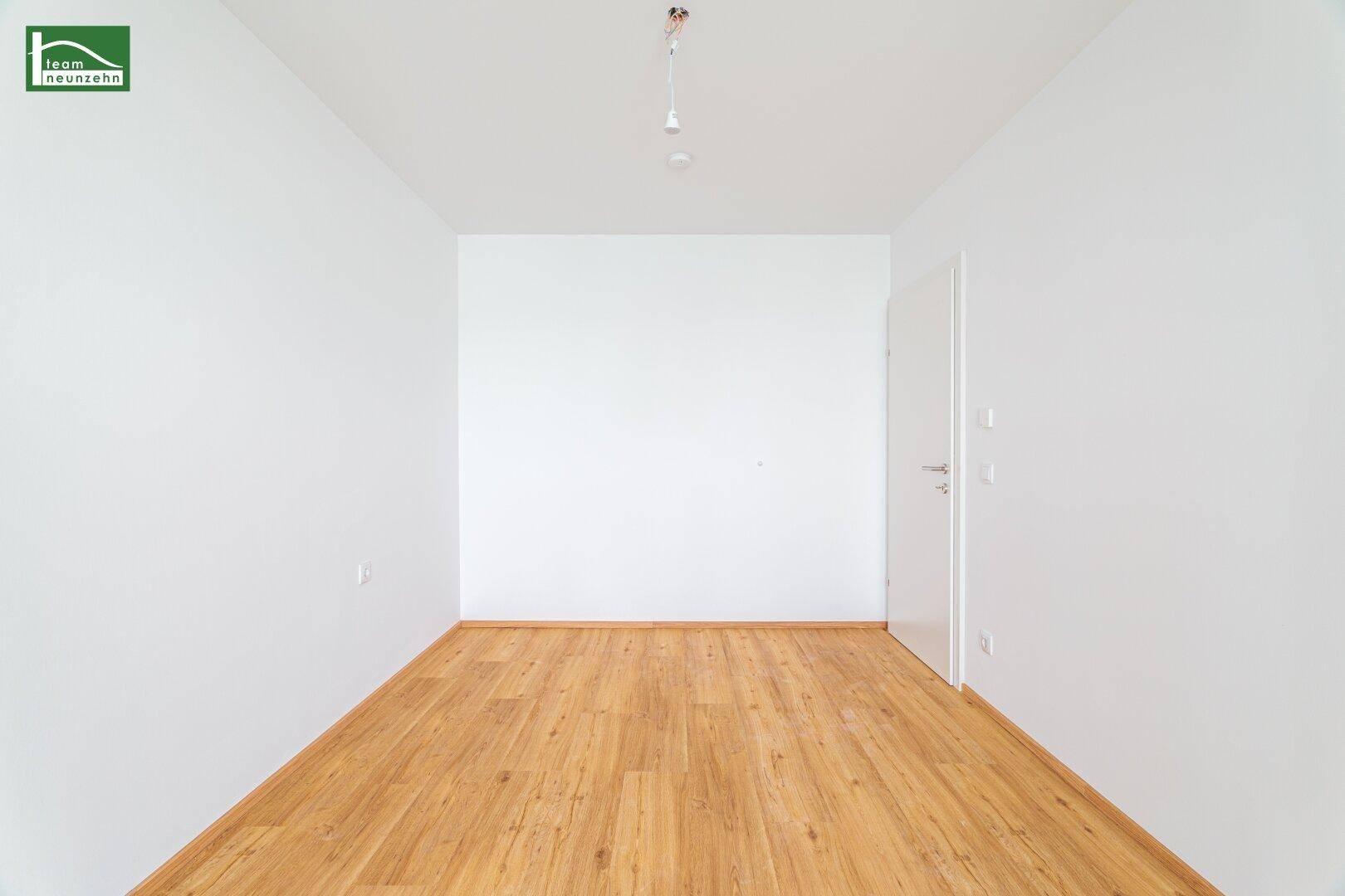 Helles, unmöbliertes Zimmer mit Holzboden und weiß gestrichenen Wänden, vielseitig nutzbar.