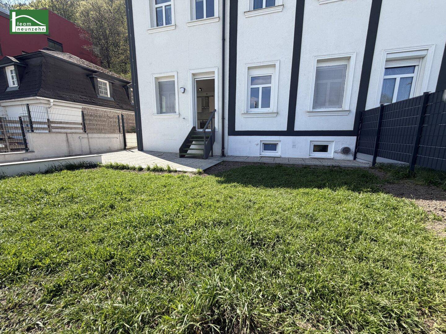 Außenbereich des Gebäudes mit Rasenfläche und gepflasterter Terrasse, ideal zum Entspannen.