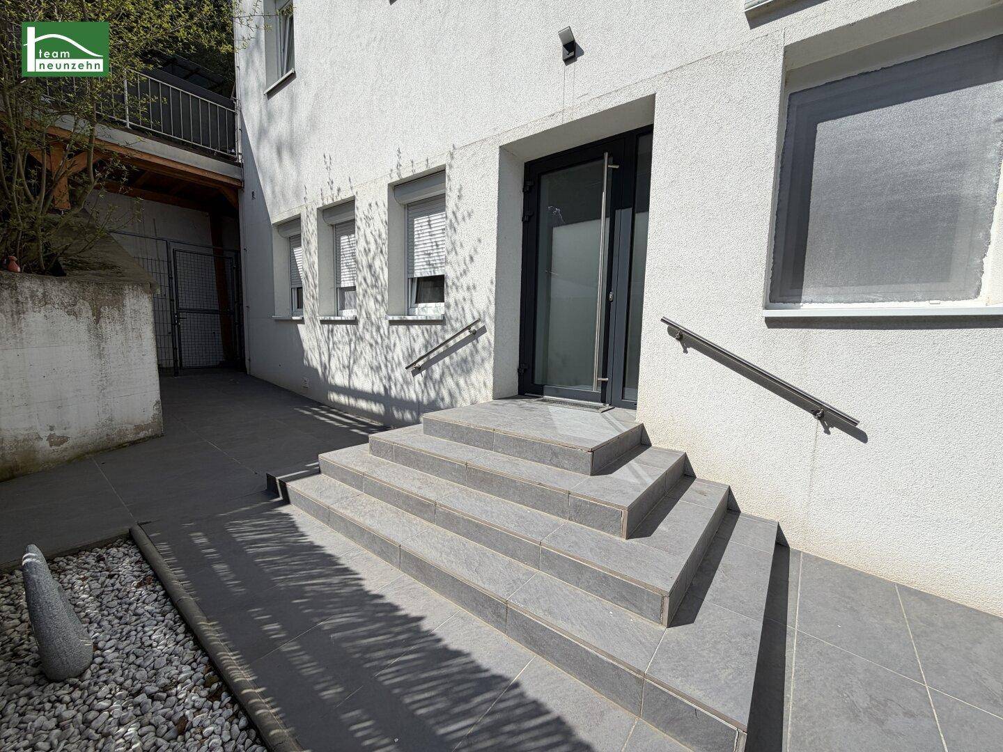 Eingangsbereich des Gebäudes mit breiter Steintreppe und modernem Türdesign.