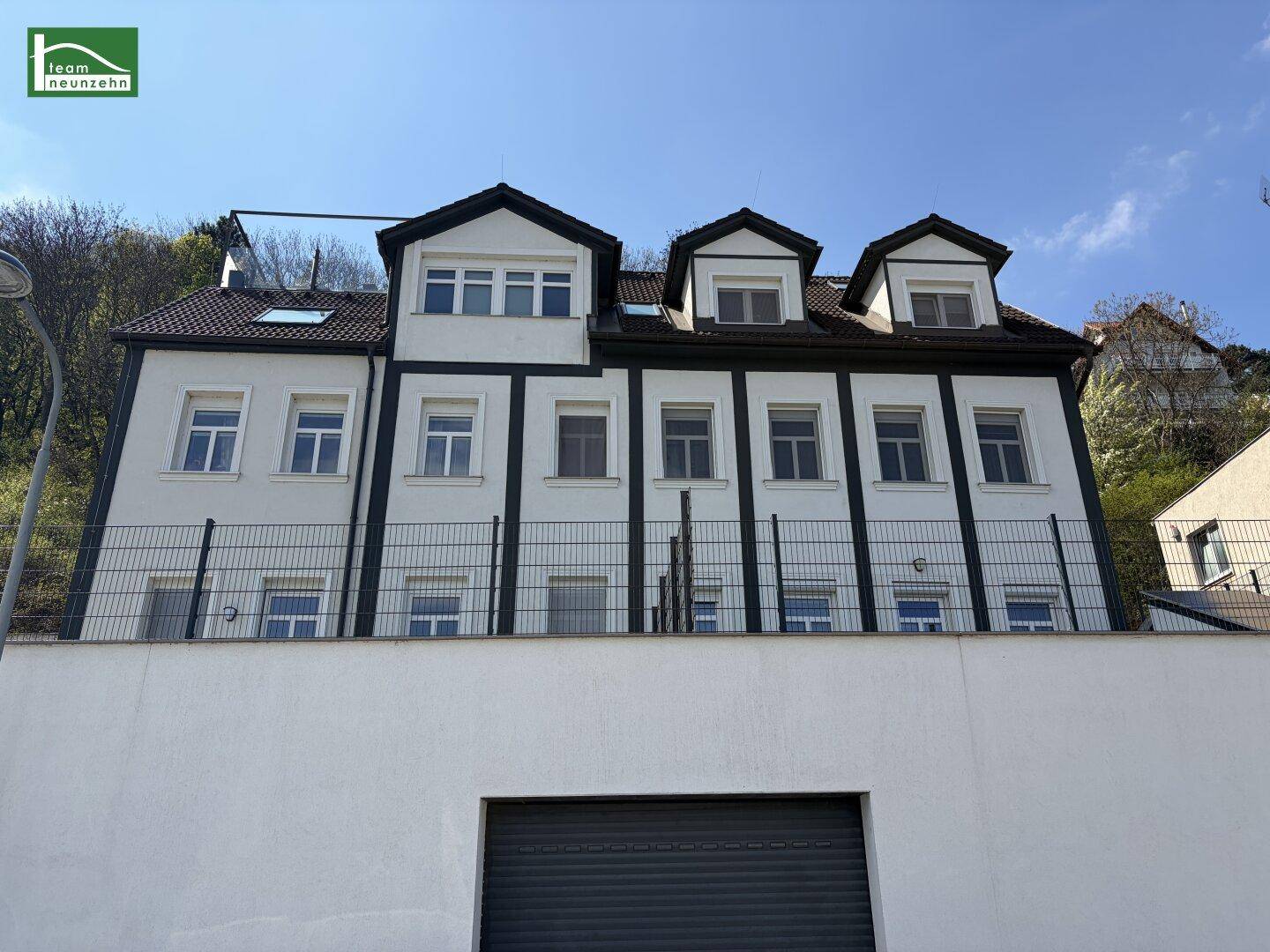 Ansicht der Gebäudefassade mit Dachgauben und moderner Architektur, eingebettet in die Umgebung.