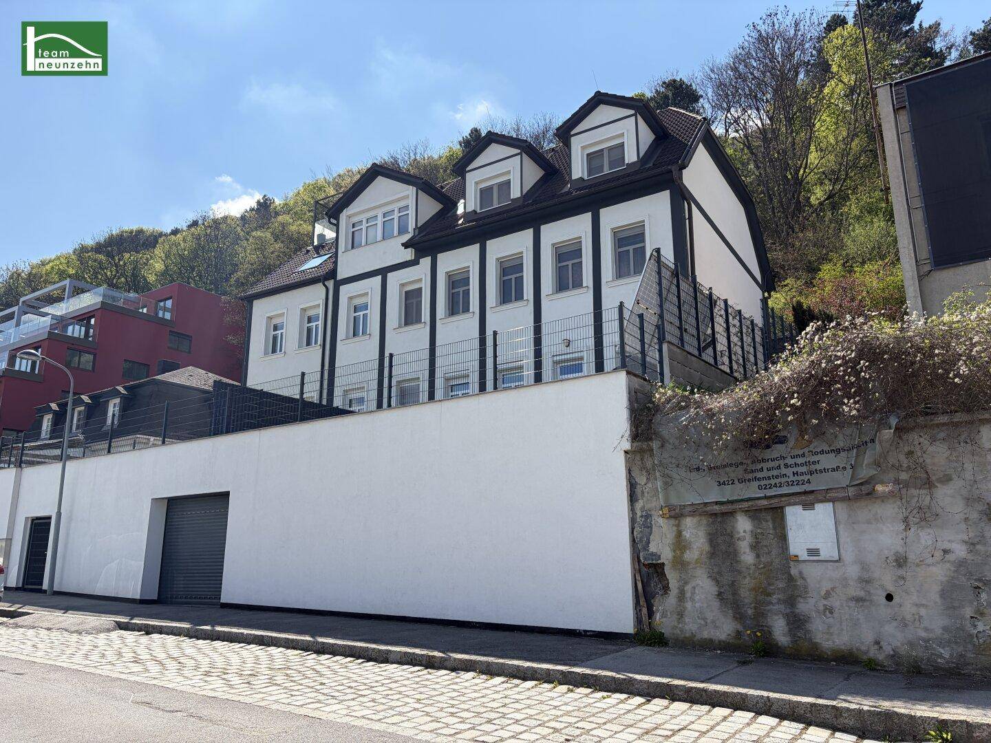 Gesamtansicht des modernen Gebäudes von der Straße aus mit Hanglage und Dachgauben.