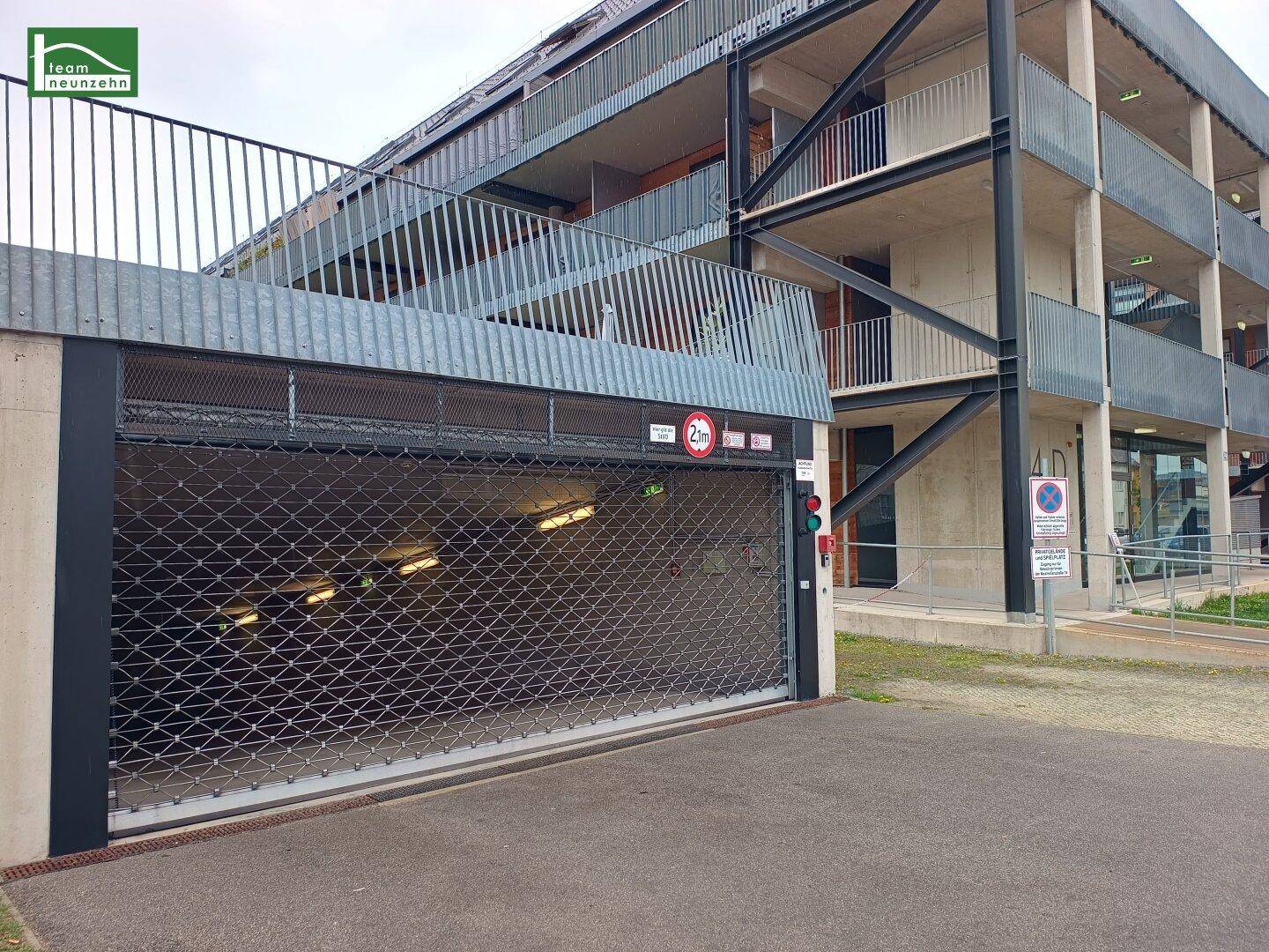 Eingang zu einer Tiefgarage mit Metallrolltor und Hinweisschildern für die Einfahrtshöhe.