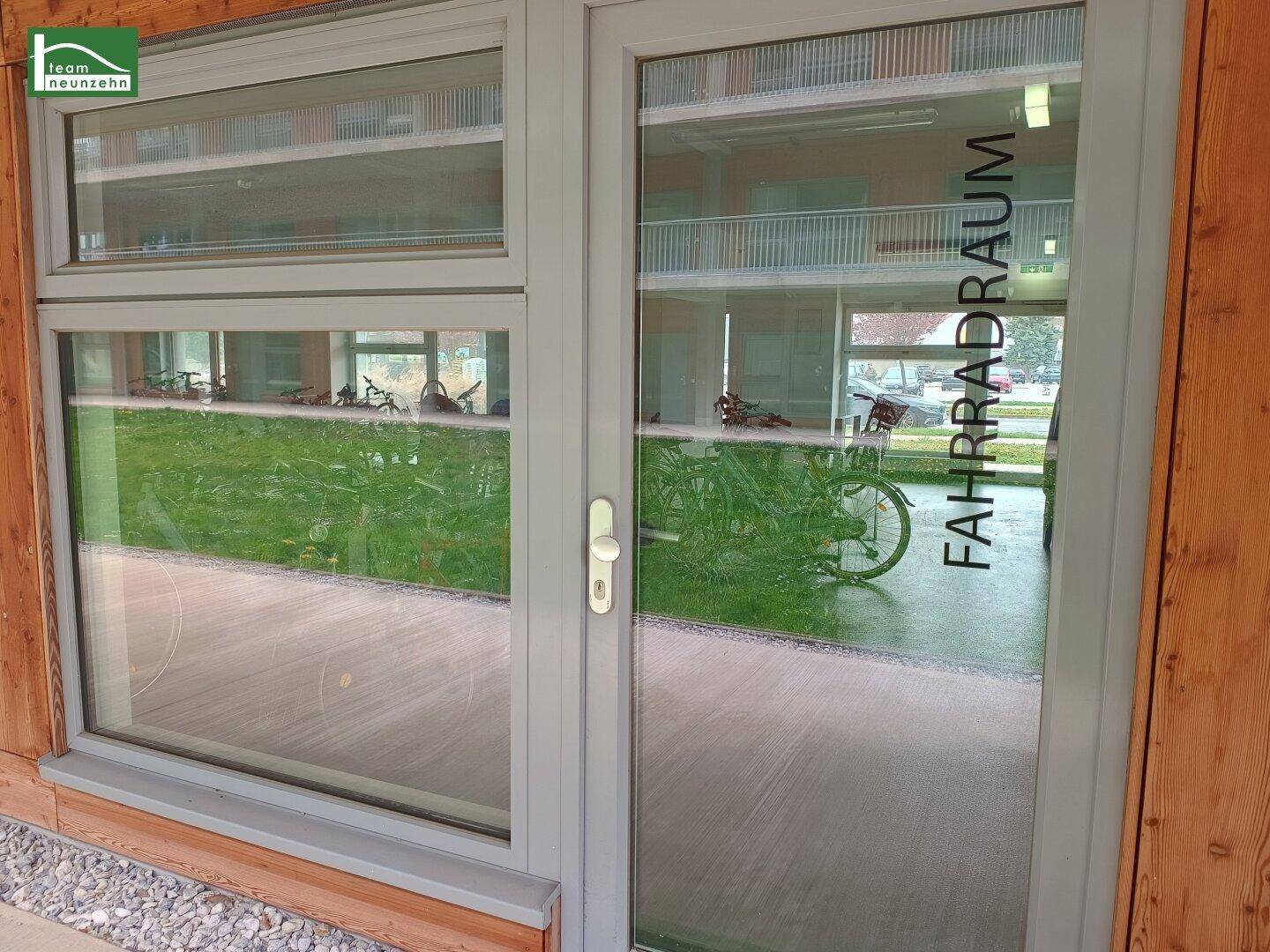 Glastür mit der Aufschrift "FAHRRADRAUM", die den Eingang zum Fahrradabstellraum des Gebäudes zeigt.