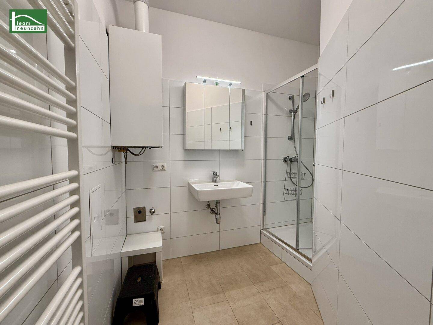 Modernes Badezimmer mit Duschkabine, Waschbecken, Spiegelschrank und beheiztem Handtuchhalter.