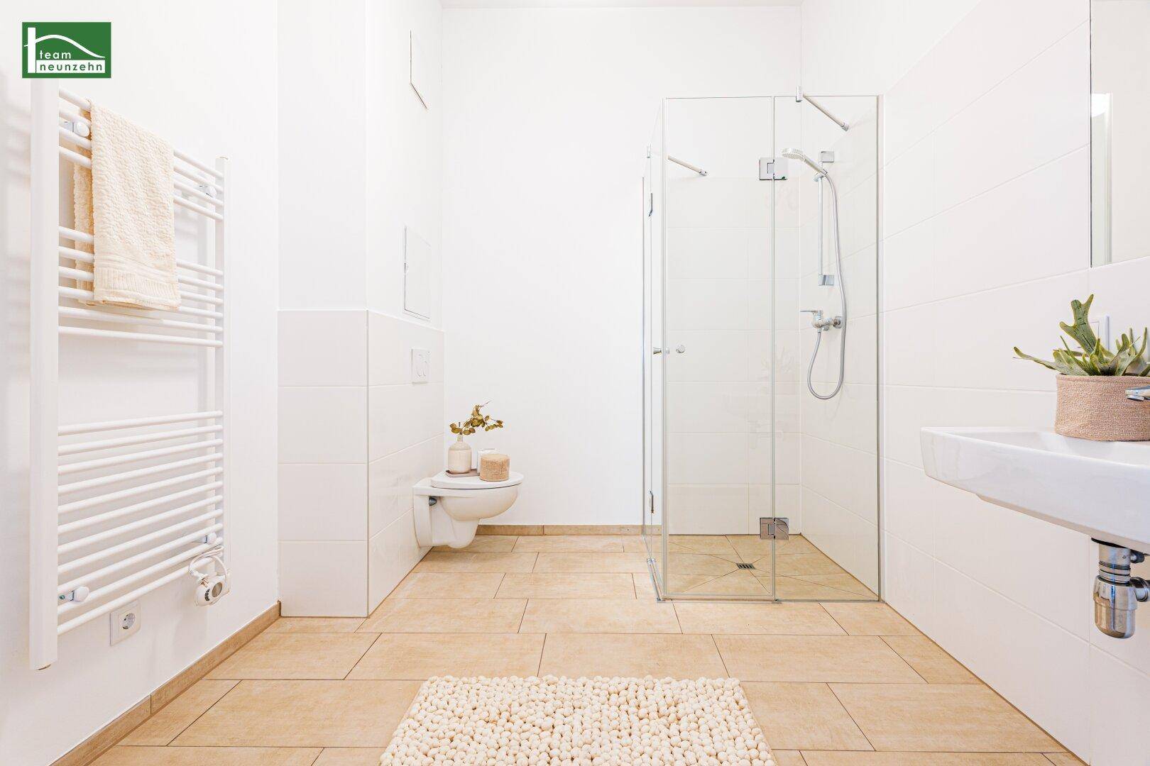 Modernes Badezimmer mit ebenerdiger Dusche, Wand-WC und Handtuchheizkörper.