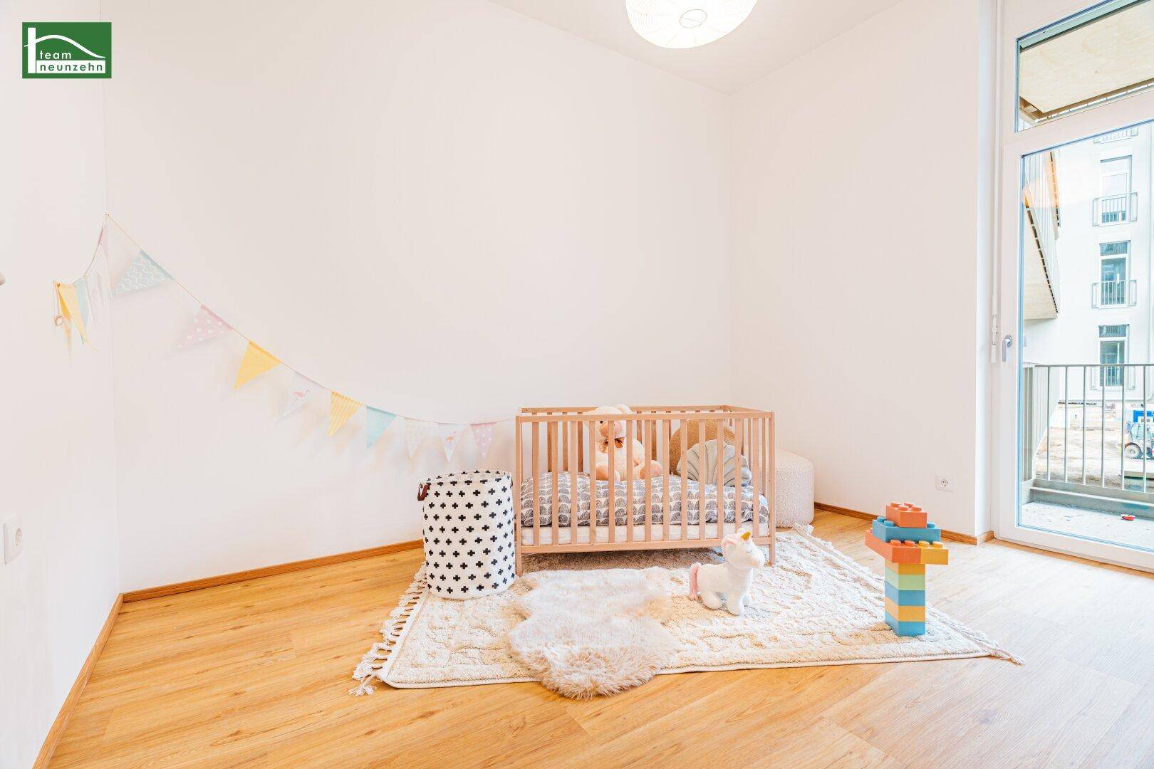 Freundliches Kinderzimmer mit Holzbett, Teppich und Zugang zum Balkon.