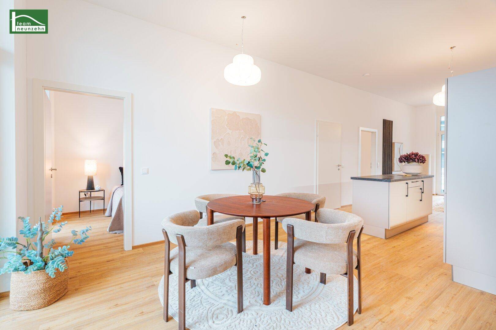 Offener Wohn- und Essbereich mit Holzboden und Zugang zu einem Schlafzimmer.