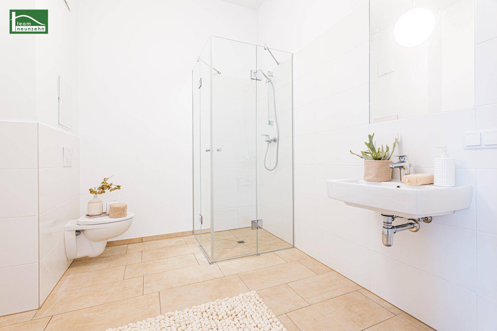 Modernes Badezimmer mit begehbarer Dusche, Wand-WC und beigen Fliesen.