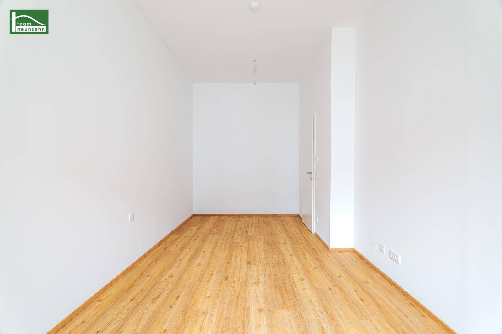 Heller, leerer Flur mit Laminatboden, der zu weiteren Räumen führt.