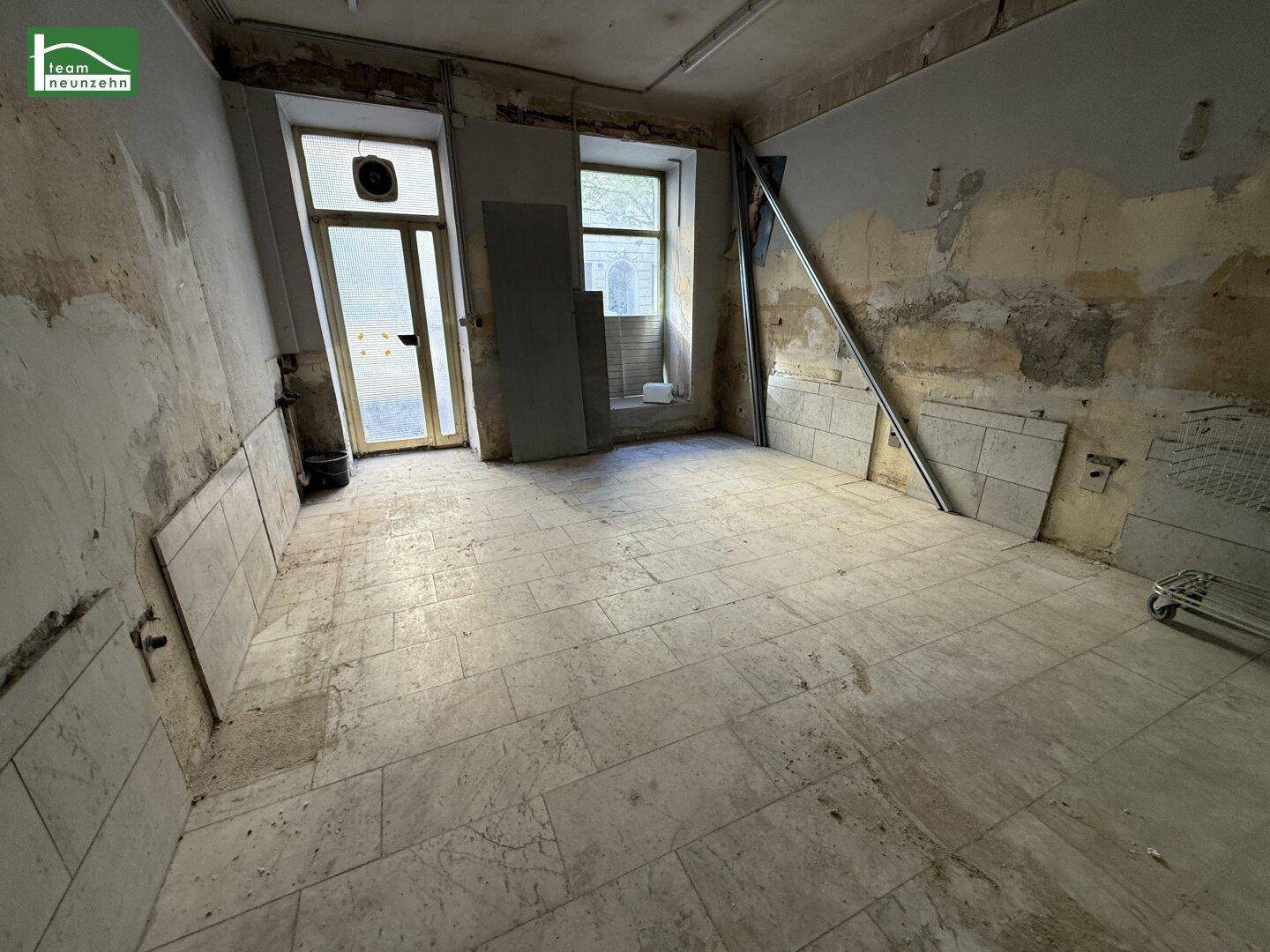 Renovierungsbedürftiger Raum mit Fliesenboden und Zugang zu einem Balkon oder einer Terrasse.