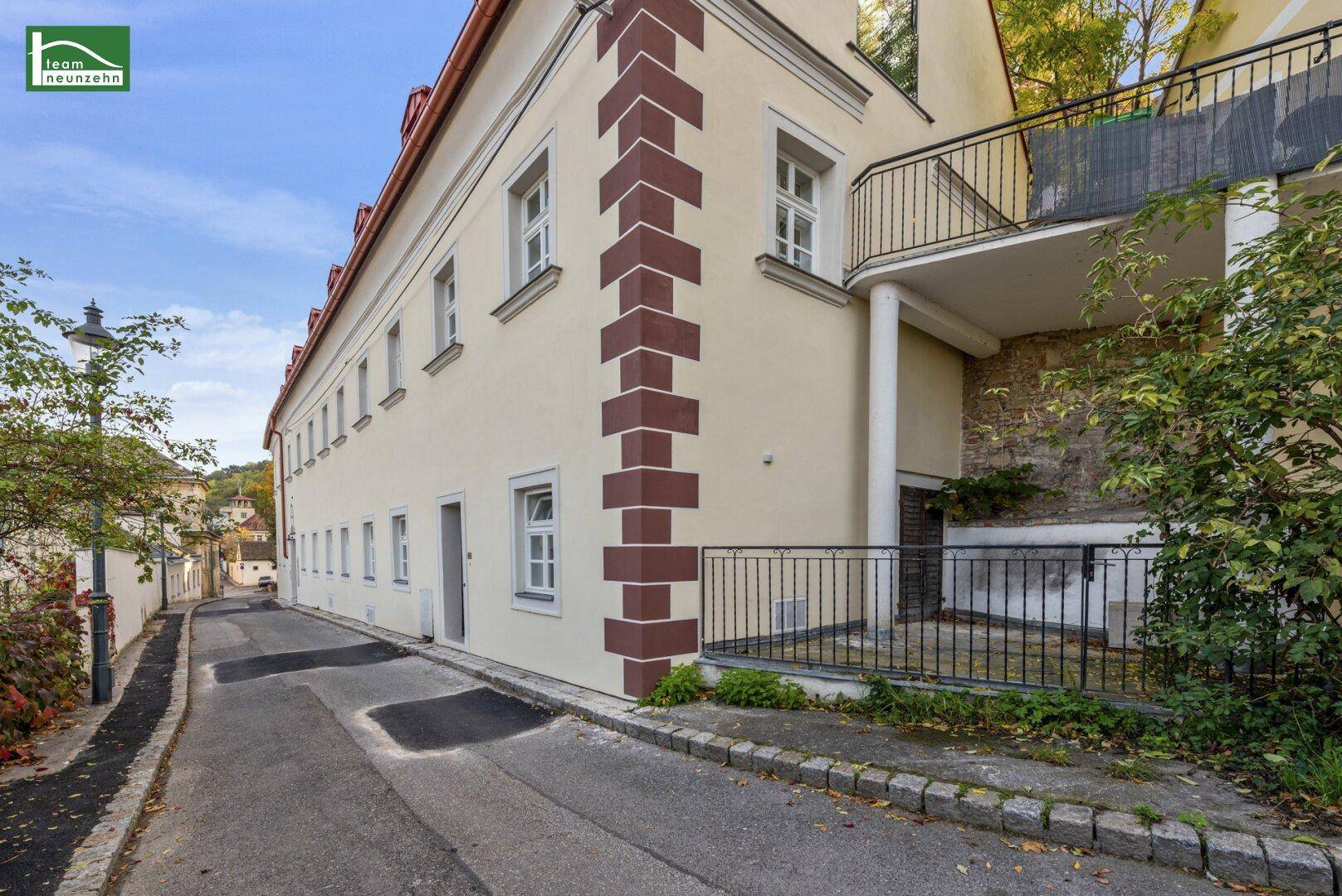 Seitenansicht eines traditionellen Gebäudes mit dekorativen Ecksteinen und einem Balkon über einer Gasse.