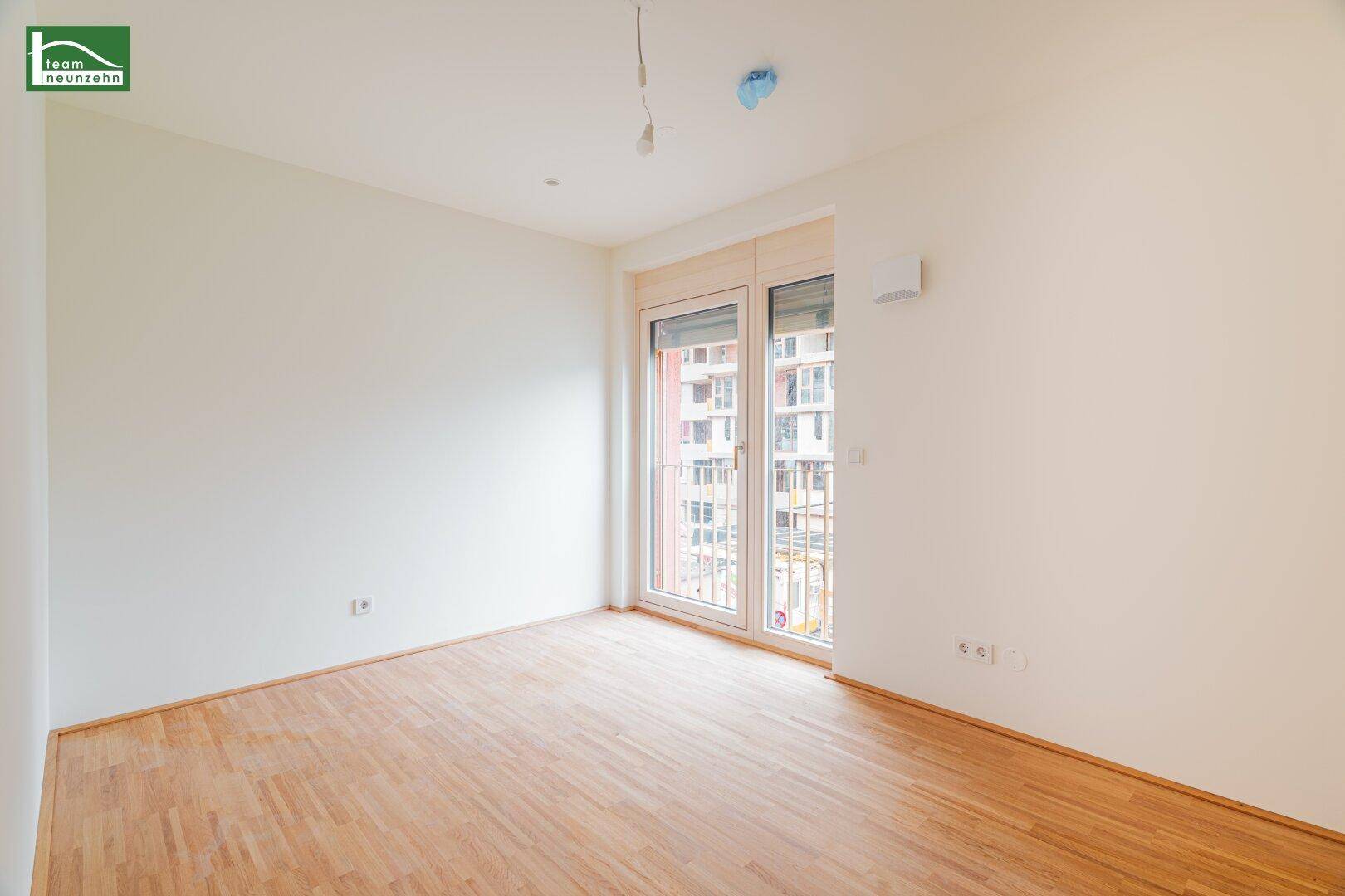 Geräumiges, helles Zimmer mit Parkettboden und Zugang zu einem Balkon, bereit zur individuellen Gestaltung.
