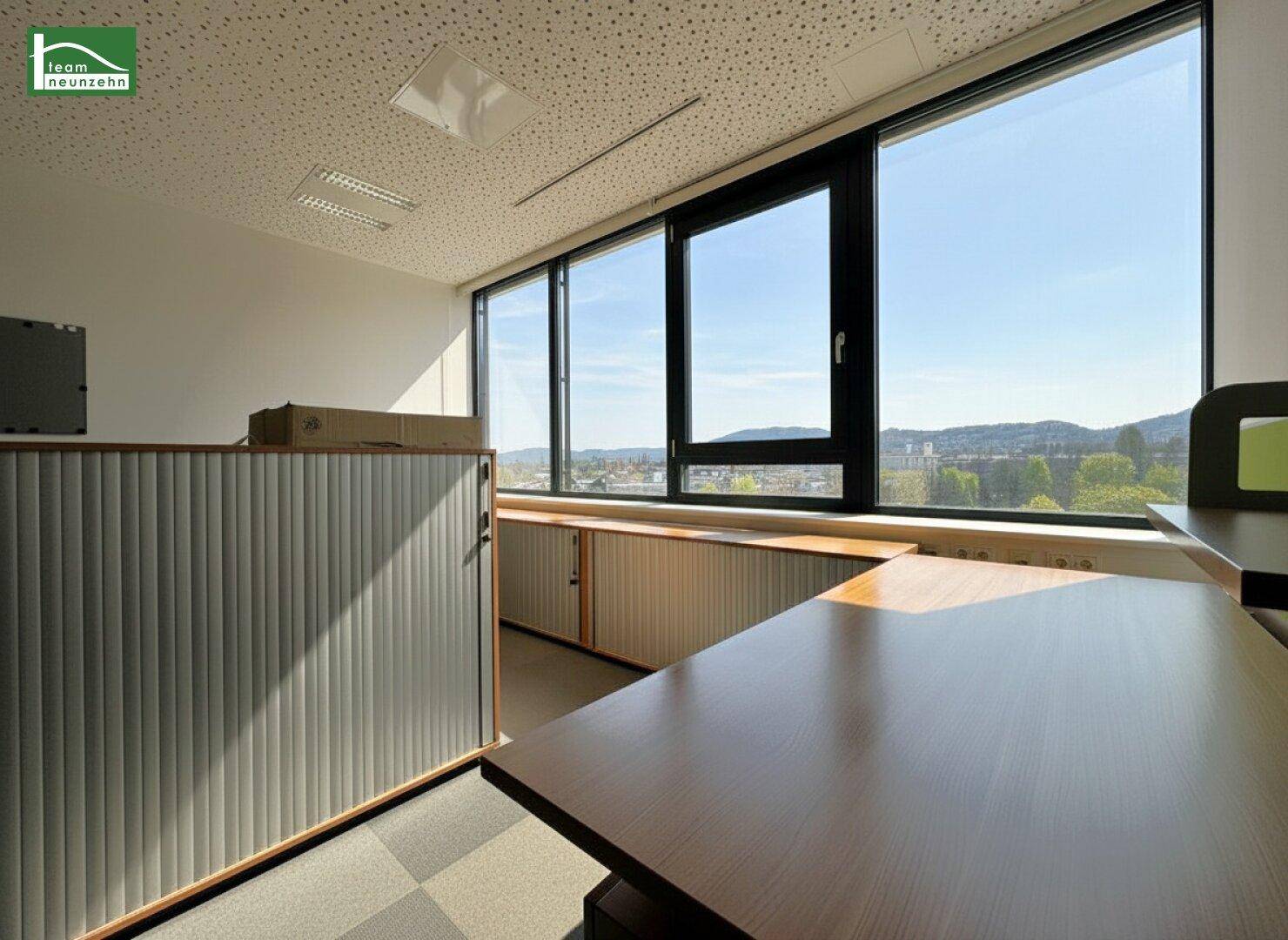 Büro mit großen Fenstern, die einen weiten Blick auf die Stadt und die umliegende Landschaft bieten.