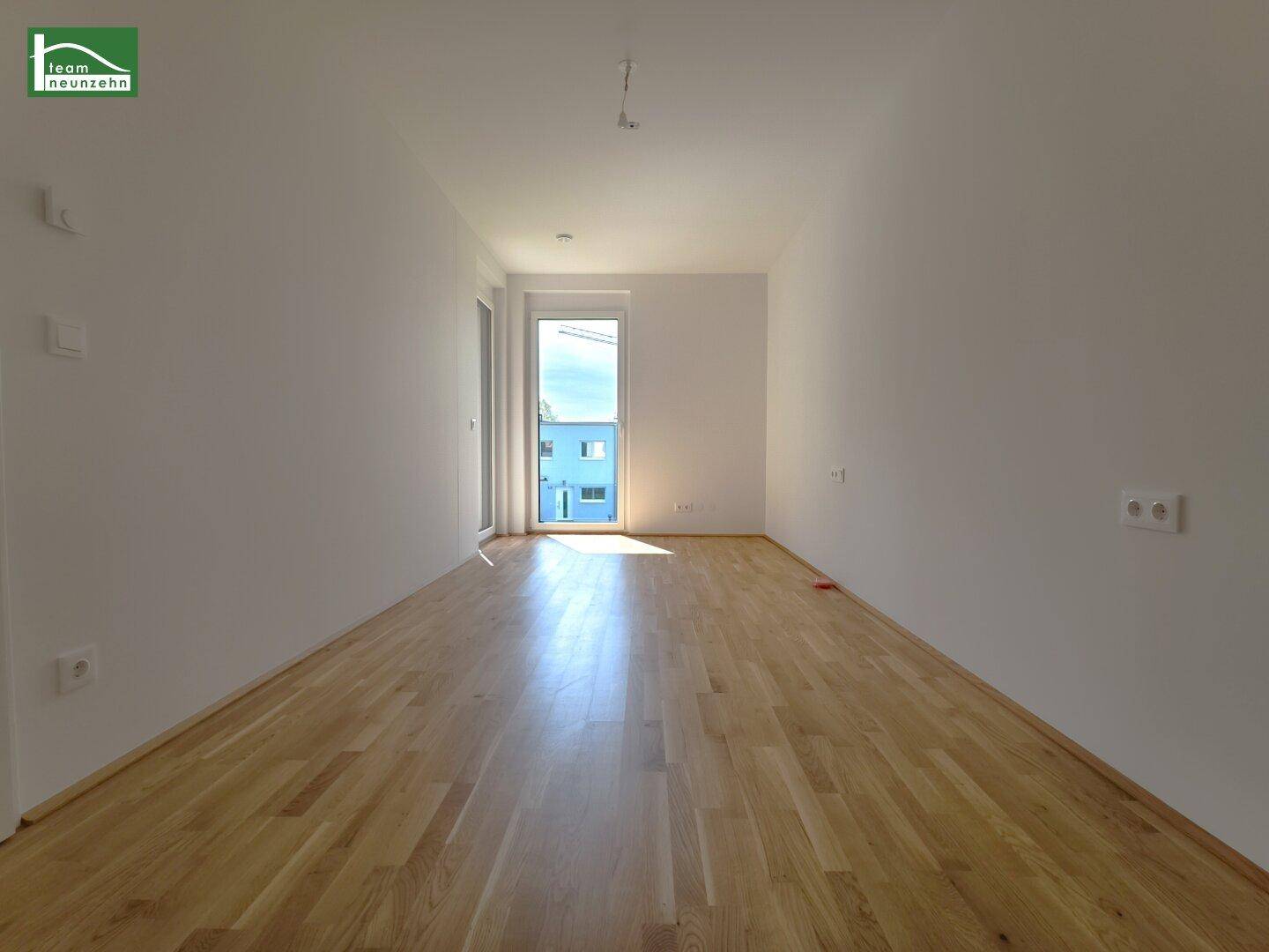 Heller Raum mit Holzboden und Zugang zu einem Außenbereich, ideal als Wohn- oder Schlafzimmer.