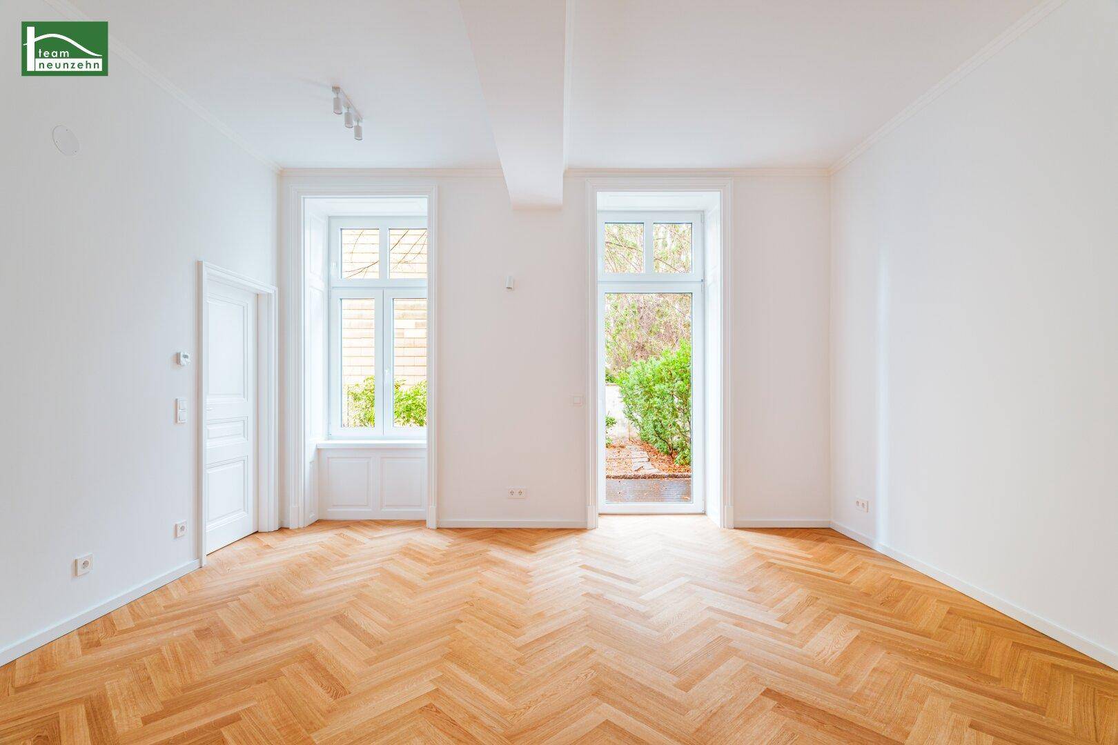 Geräumiges Zimmer mit Fischgrätparkett und großen Fenstern zum Garten.