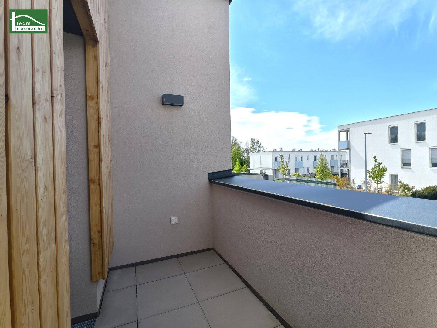 Kleiner Balkon mit Fliesenboden und Holzelementen am modernen Gebäude.