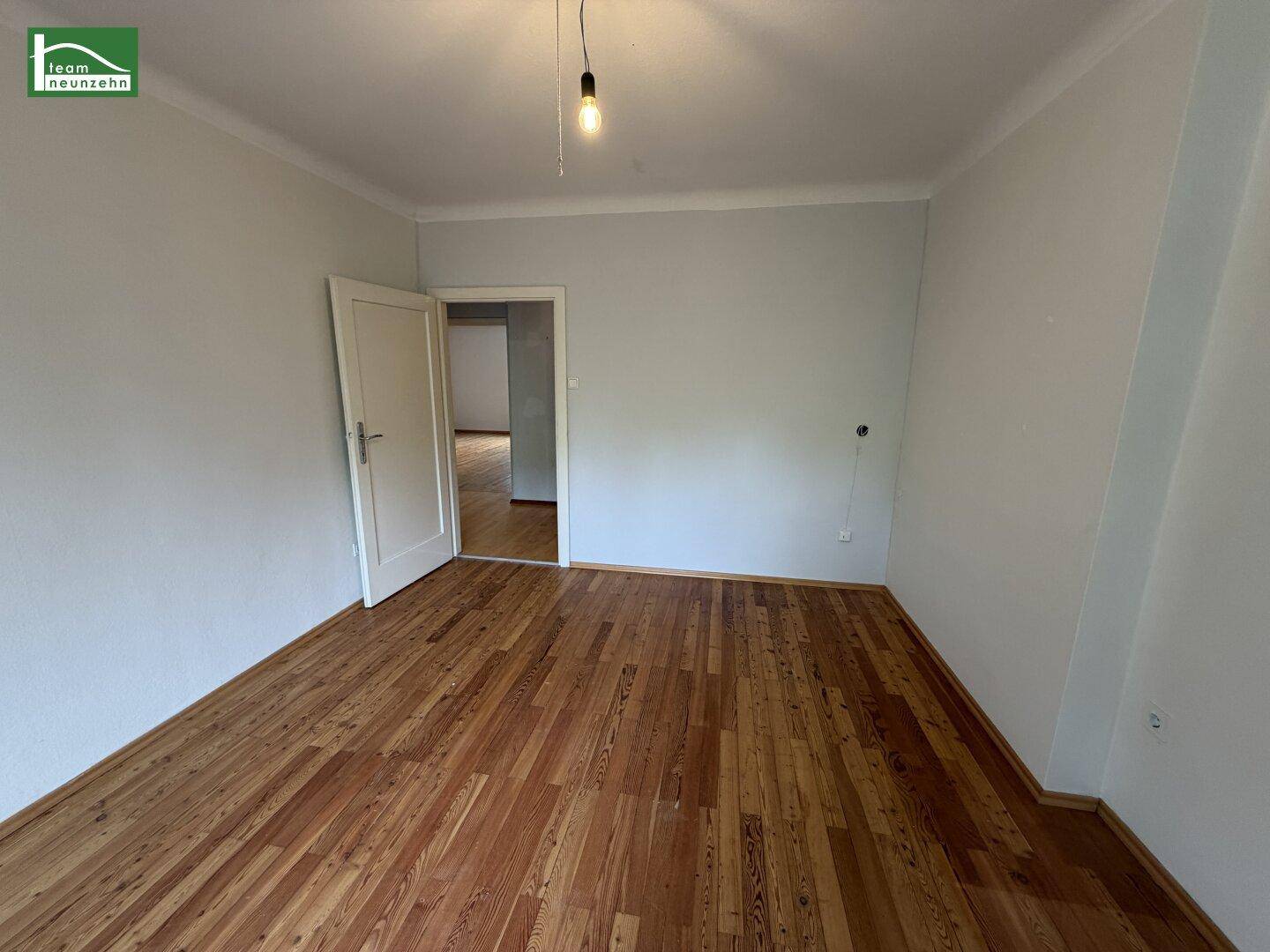 Leeres Schlafzimmer mit Holzparkettboden und weiß gestrichenen Wänden, bereit zur Einrichtung.