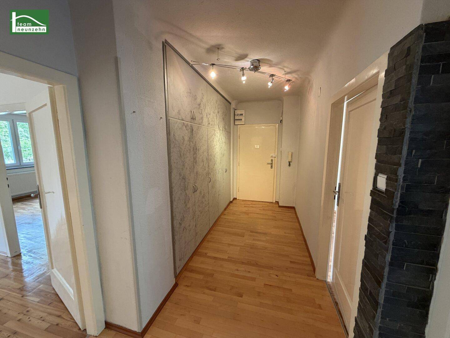 Heller Flur mit Holzparkettboden und praktischen, integrierten Wandschränken.