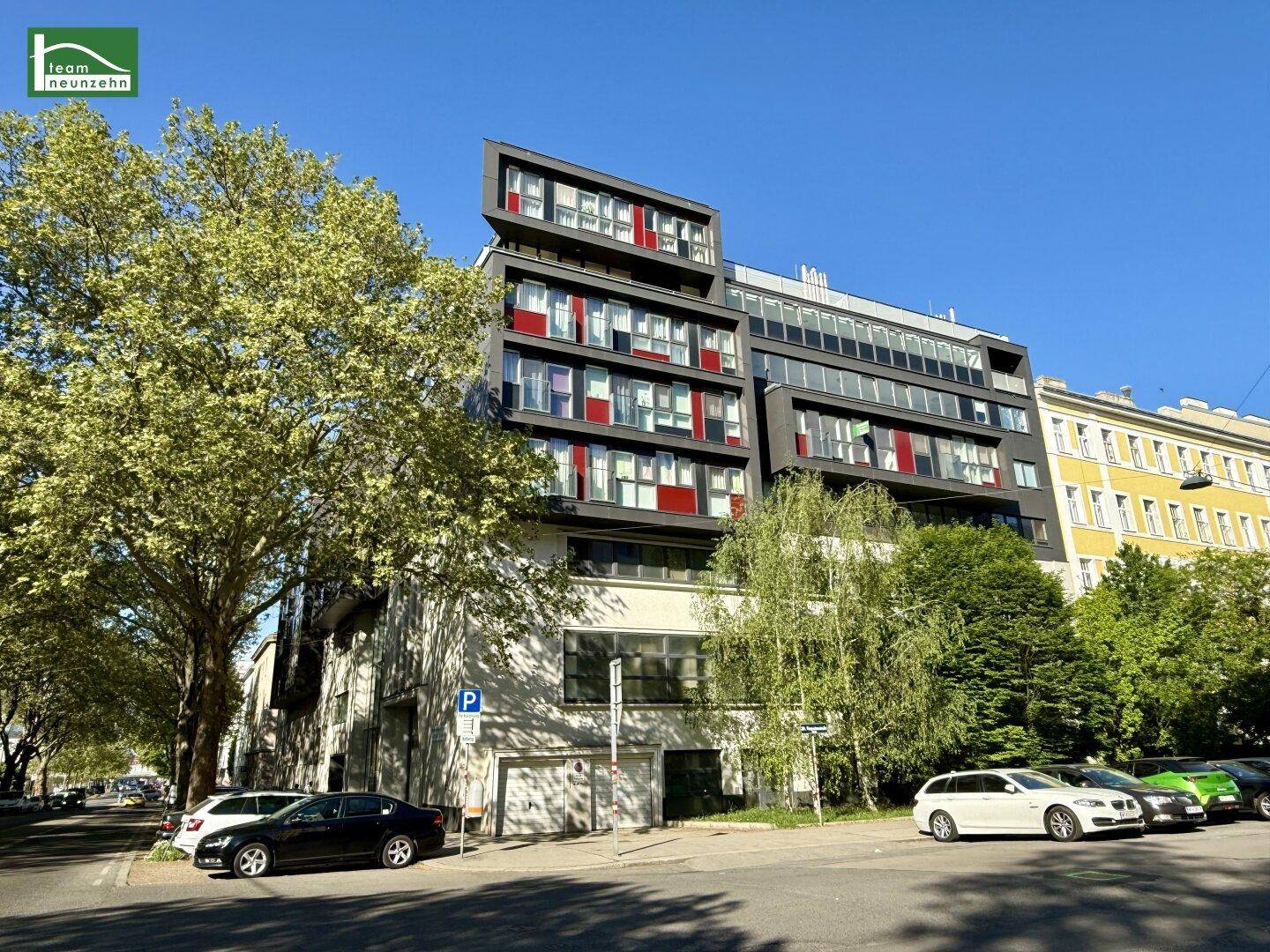 Modernes Wohngebäude mit markanter Architektur und großen Fenstern an einer sonnigen Stadtstraße.