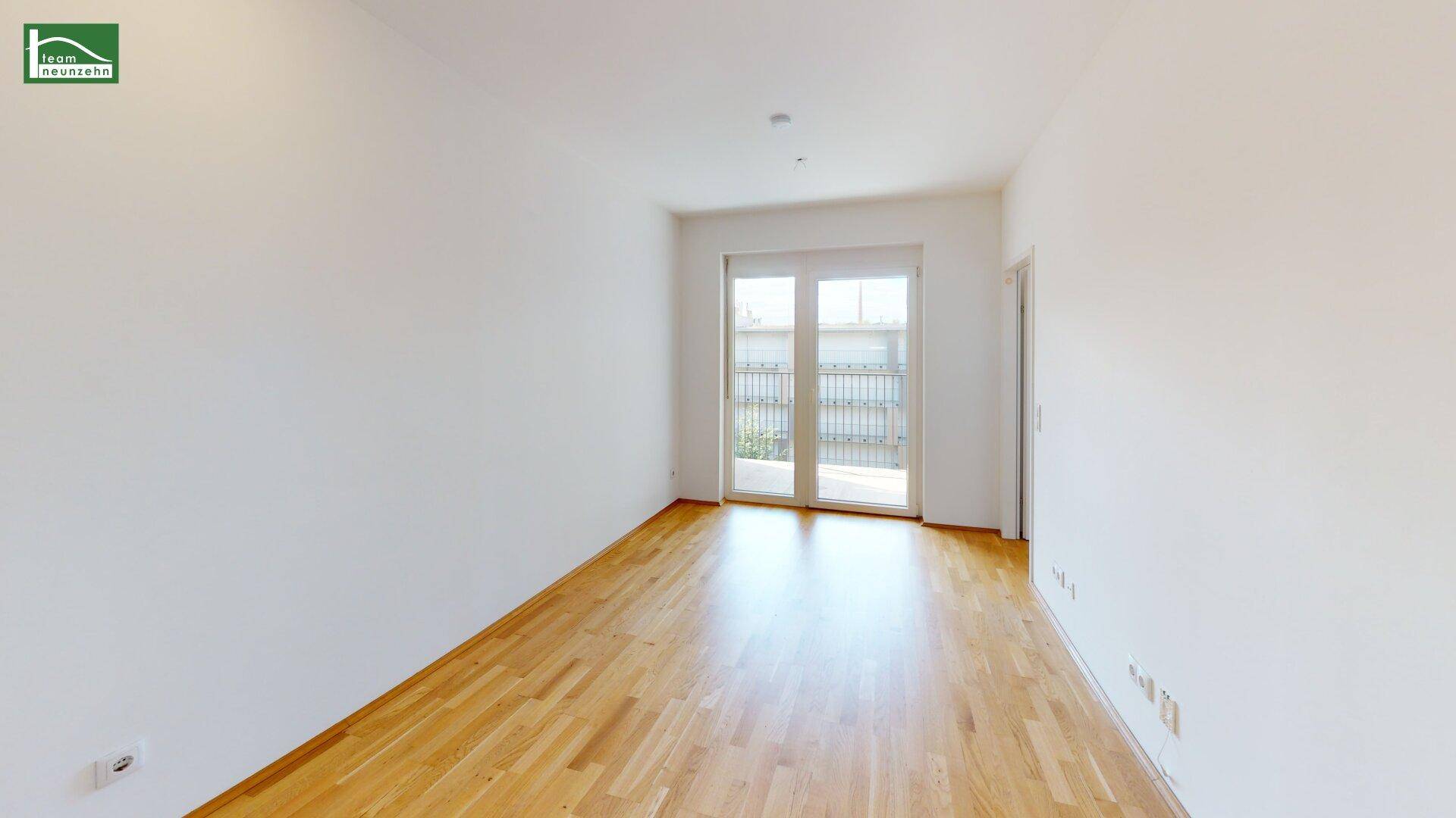Langes, helles Zimmer mit Parkettboden und großen Fenstern, ideal für Wohnzwecke.
