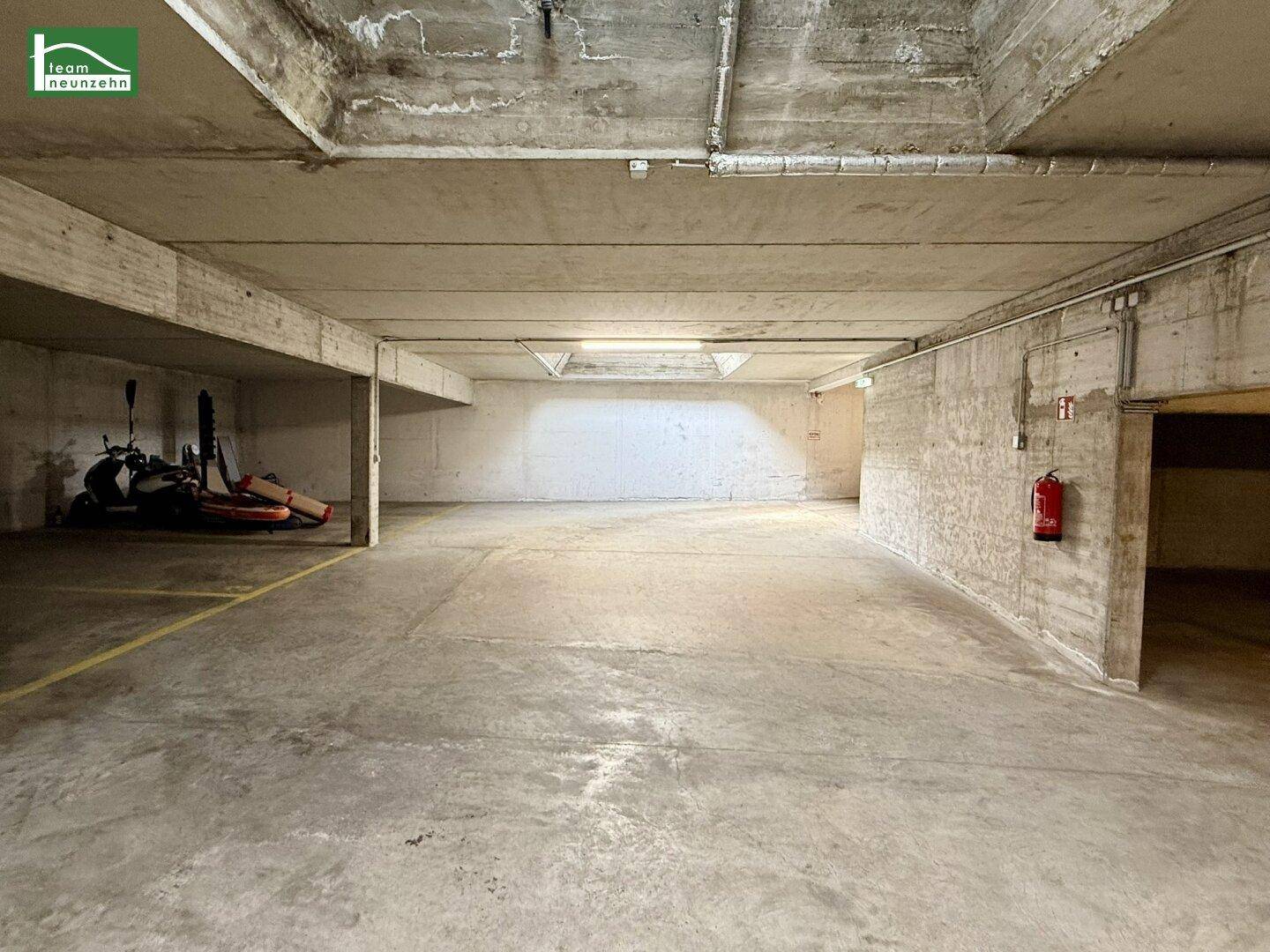 Geräumige Tiefgarage mit Betonboden und Beleuchtung, bietet viel Platz für Fahrzeuge.