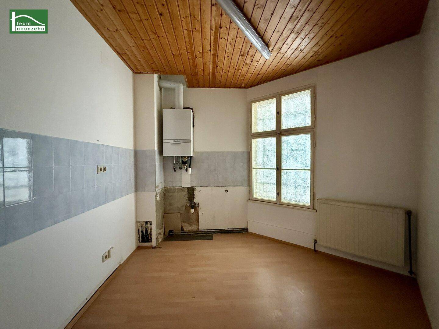 Unfertige Küche mit Holzdecke, Gastherme und gefliestem Wandbereich, bereit für die Installation.