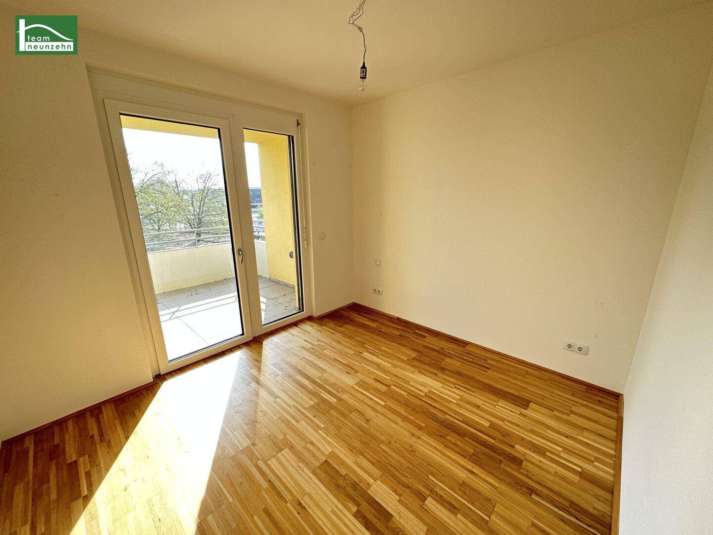 Helles Schlafzimmer mit Holzboden und direktem Zugang zu einem sonnigen Balkon.