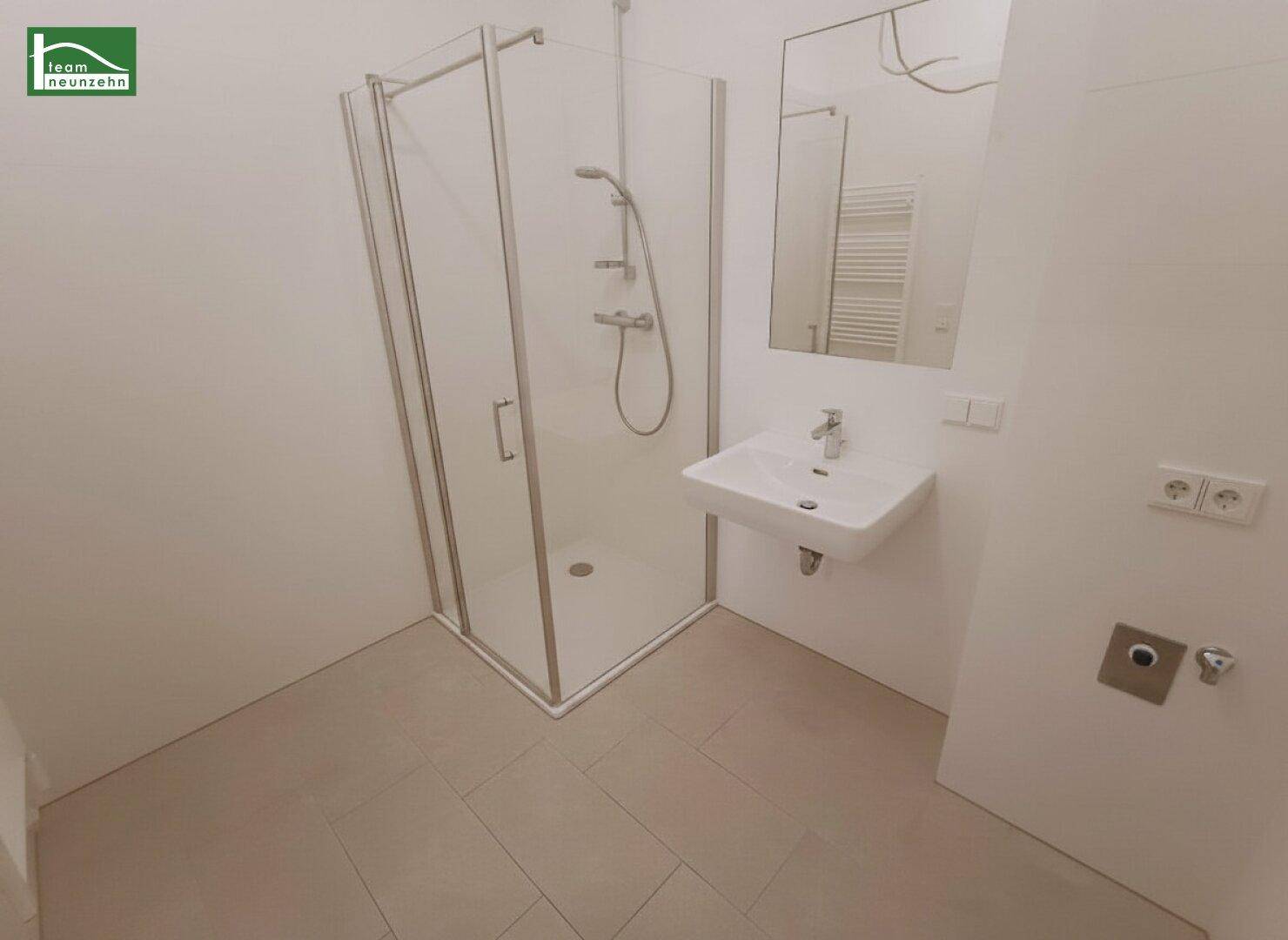Modernes Badezimmer mit Duschkabine, Waschbecken und beheiztem Handtuchhalter.