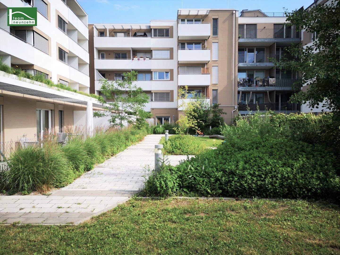 Gepflegter Innenhof mit Grünflächen, Gehwegen und Bäumen, ideal zur Erholung.