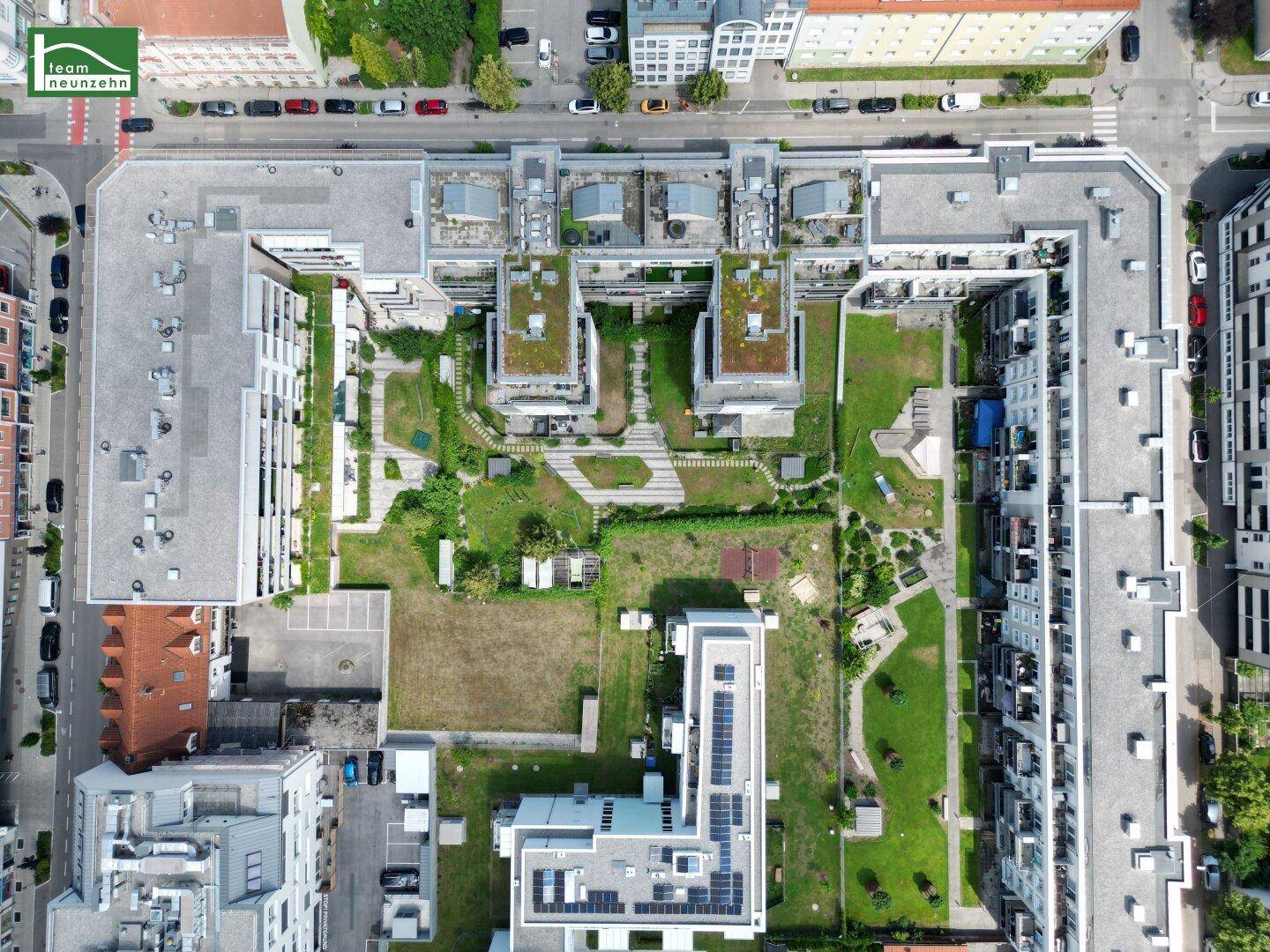 Vogelperspektive eines modernen Wohnkomplexes mit begrünten Dächern und Innenhöfen.