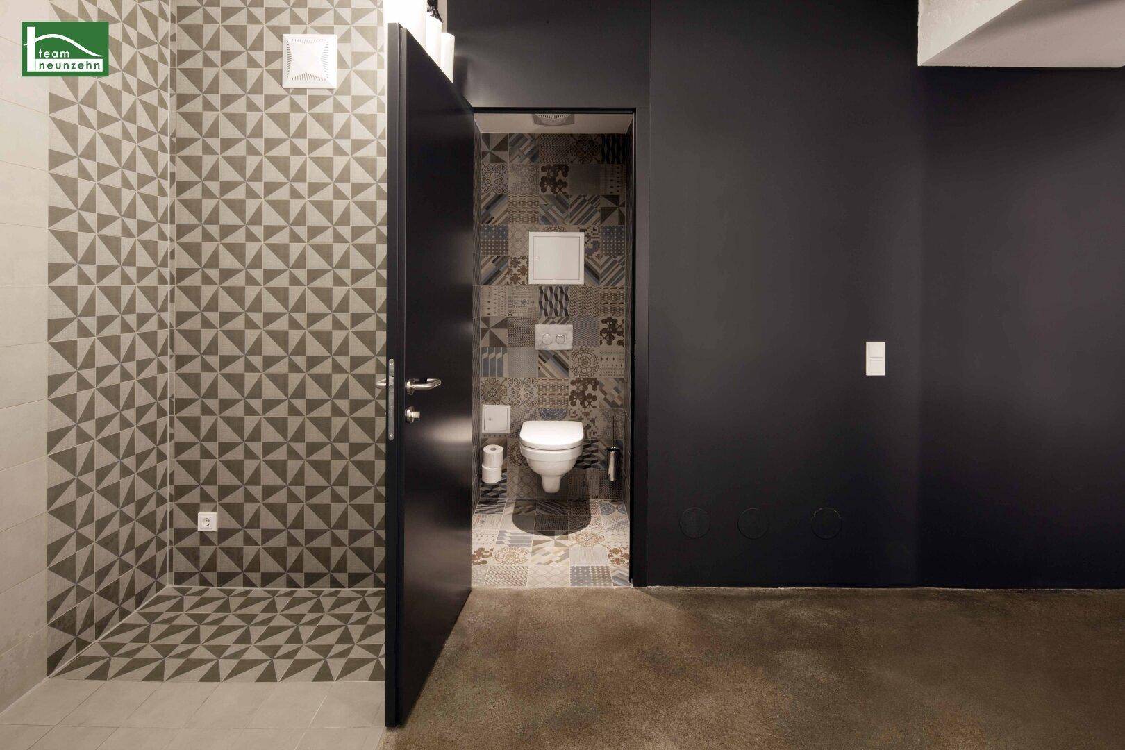 Separate Toilette mit gemusterten Fliesen und Wand-WC in modernem Design.