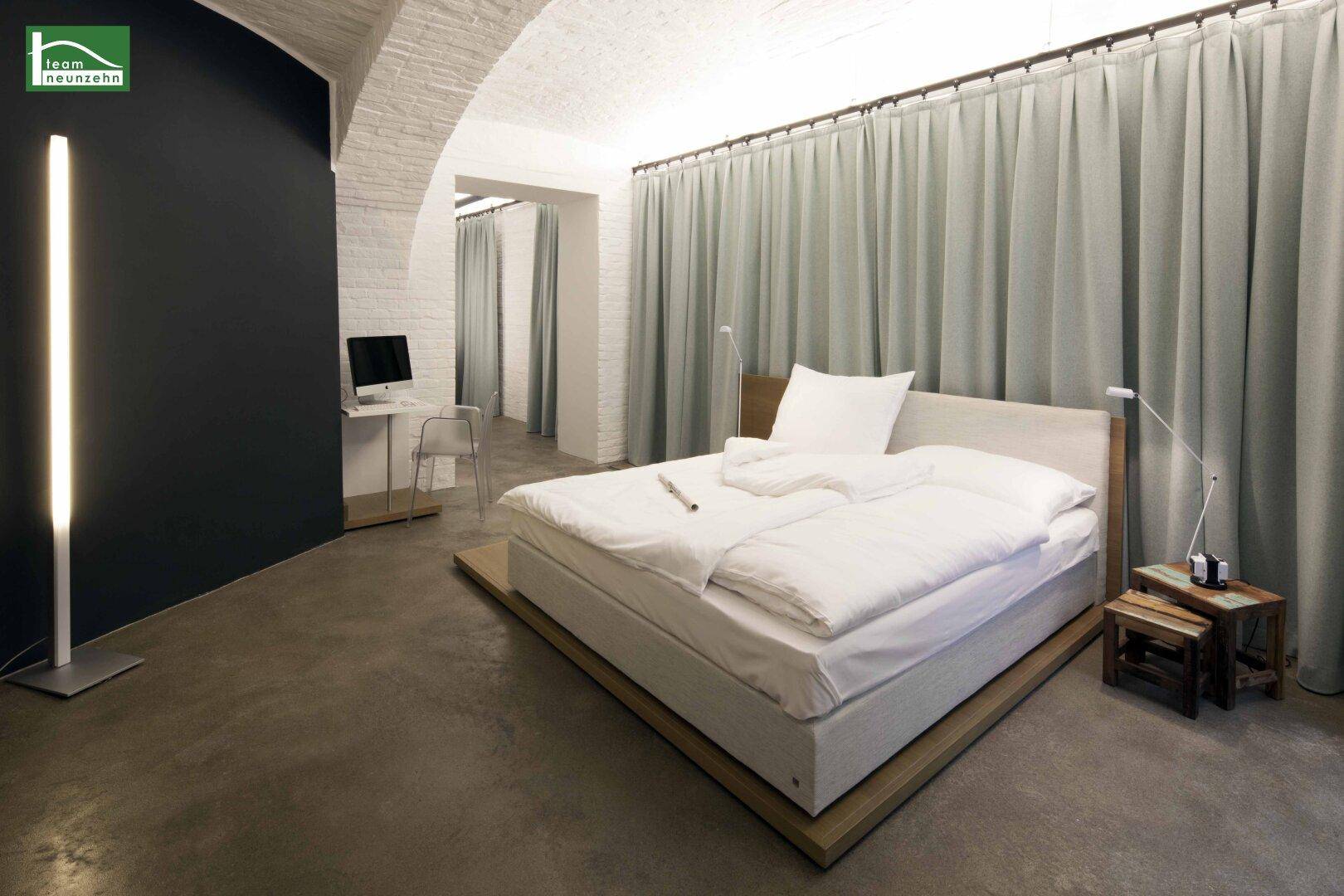 Geräumiges Schlafzimmer mit großem Bett, Vorhängen und Stehlampe in modernem Ambiente.