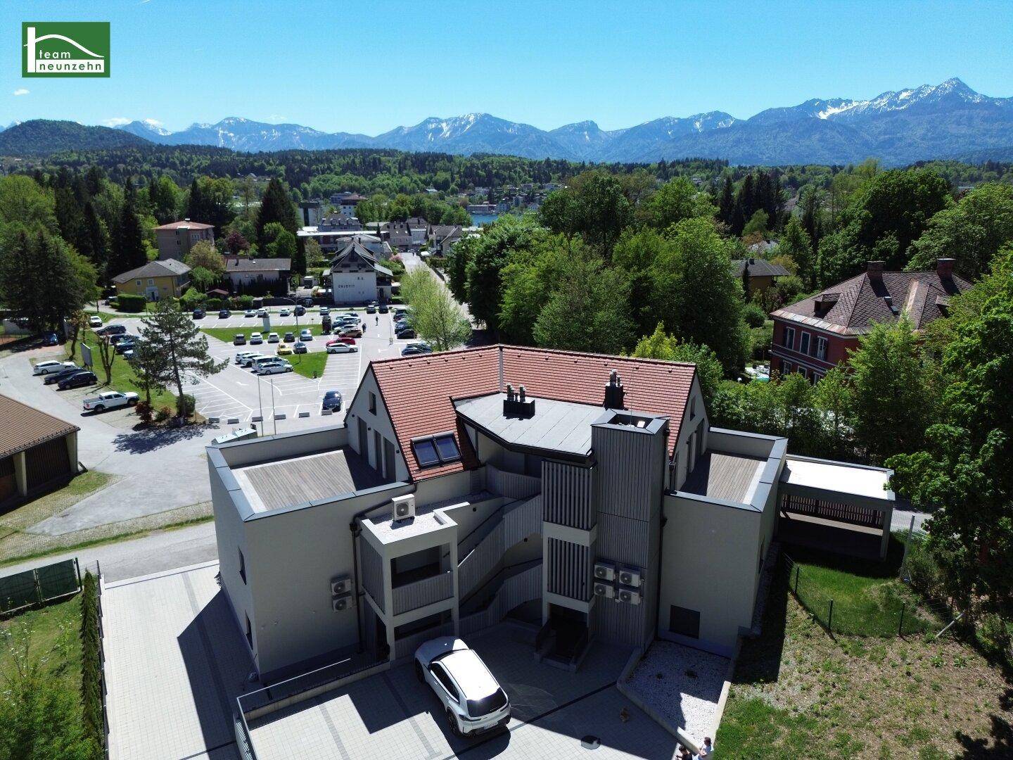 Luftaufnahme einer modernen Wohnanlage mit Bergblick und umliegender Infrastruktur.