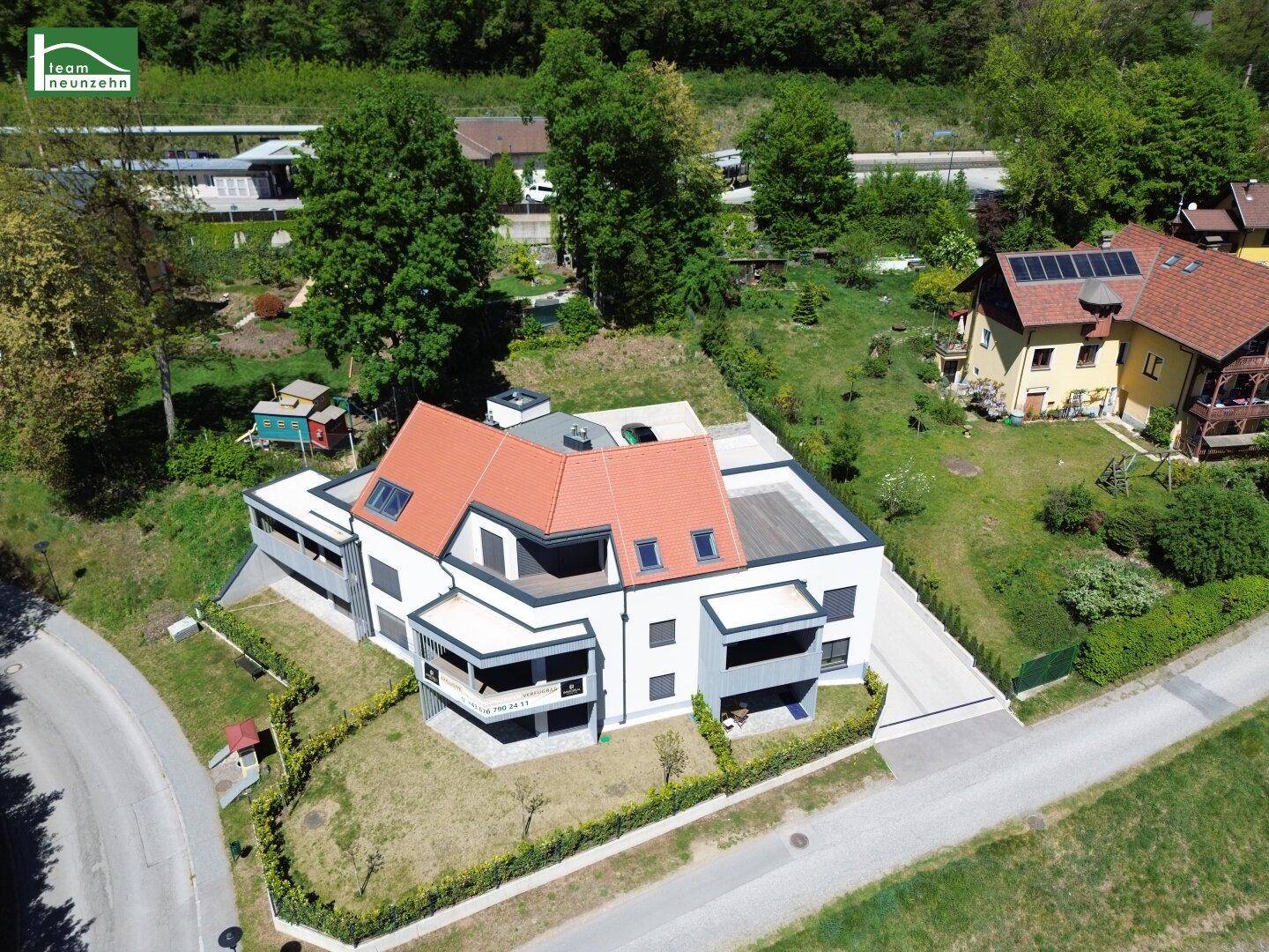 Moderne Wohnanlage von oben mit großzügigen Außenbereichen und umliegender Natur.