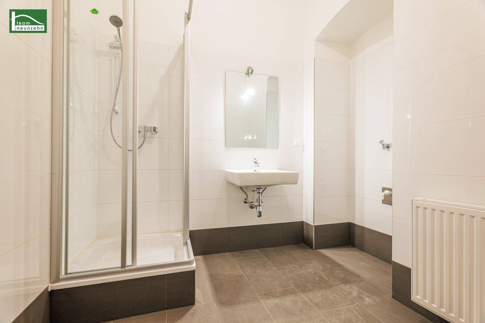 Modernes Badezimmer mit Duschkabine, Waschbecken und hellen Fliesen.