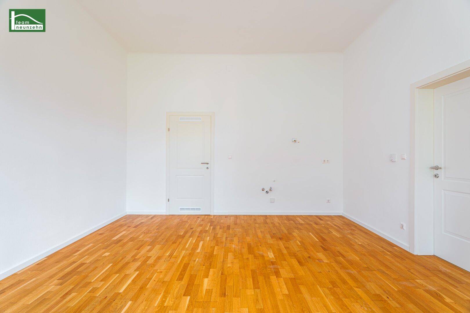 Leeres Zimmer mit Holzboden und weiß gestrichenen Wänden, ideal für individuelle Gestaltung.