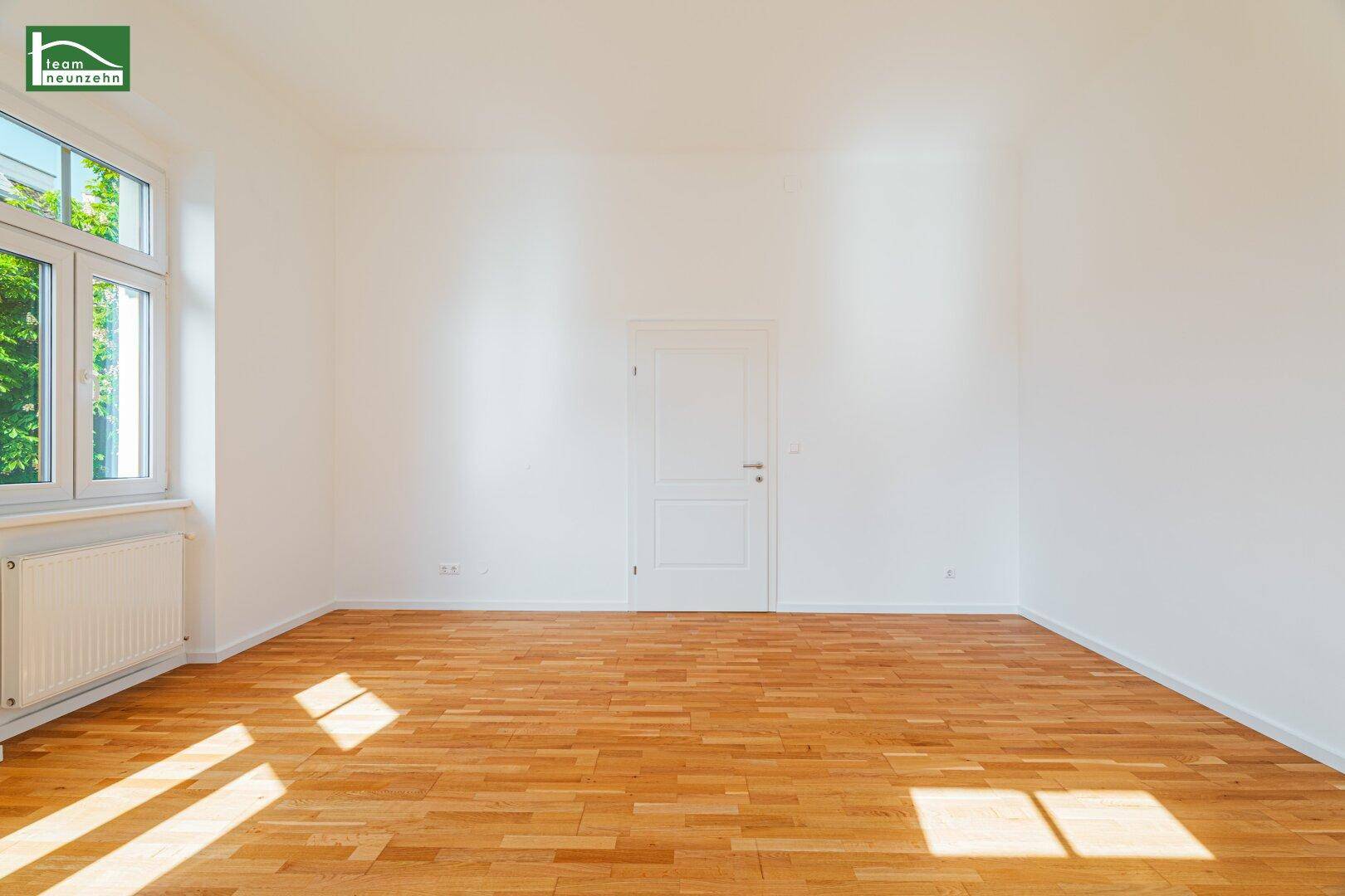Geräumiges, helles Zimmer mit Holzboden und weiß gestrichenen Wänden, bereit zur Einrichtung.