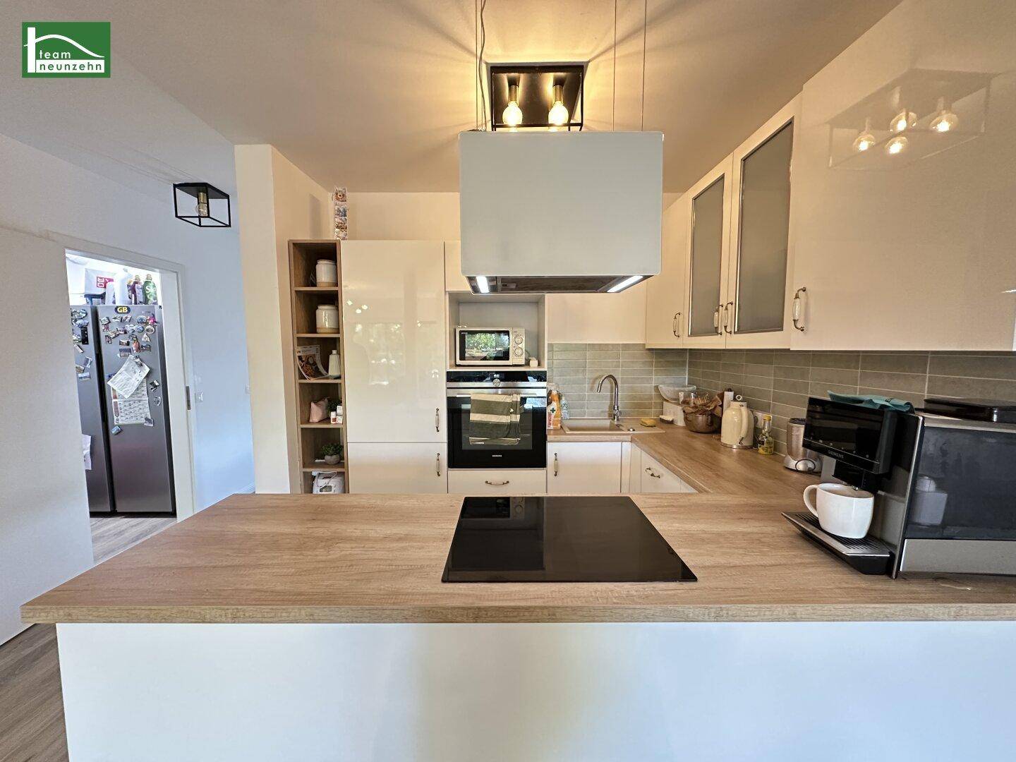 Moderne Küche mit weißen Schränken, Holz-Arbeitsplatte und integrierten Geräten.