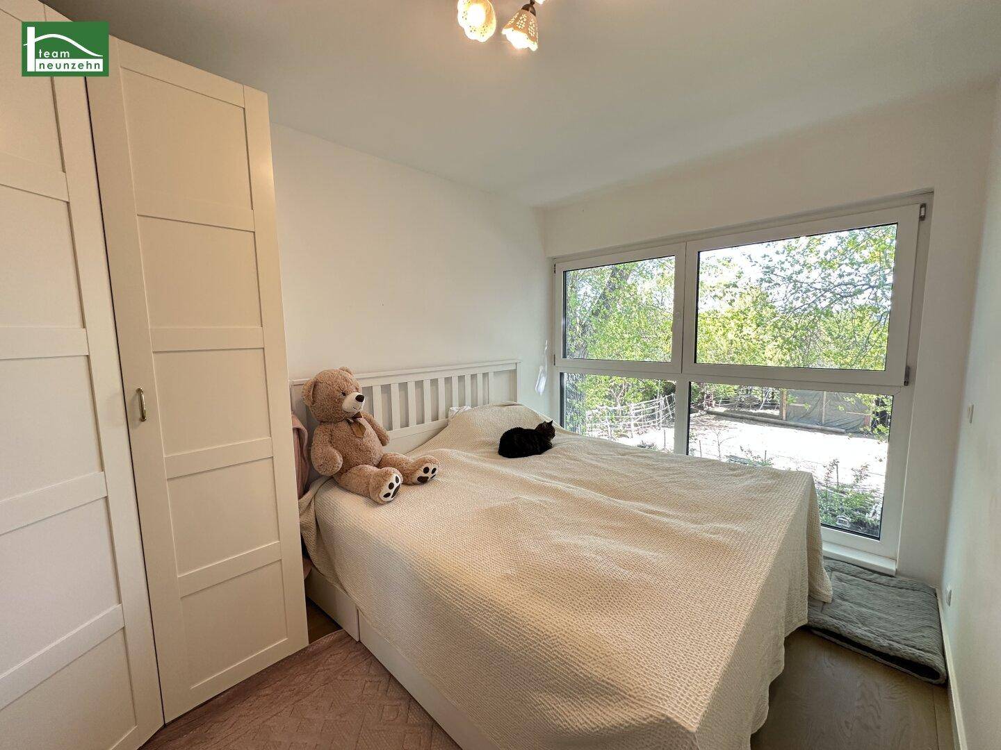 Gemütliches Schlafzimmer mit großem Bett, weißem Kleiderschrank und Blick ins Grüne.