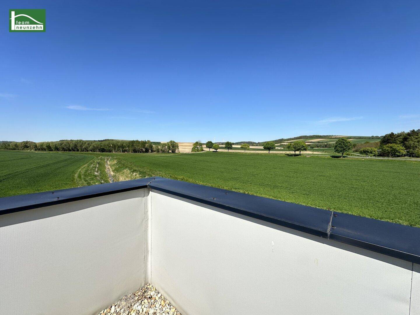 Weitläufiger Blick von der Dachterrasse über grüne Felder und die umliegende Landschaft.