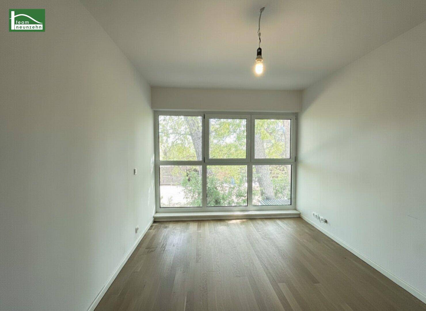 Helles Zimmer mit Holzboden und großen Fenstern, ideal als Schlaf- oder Arbeitszimmer.