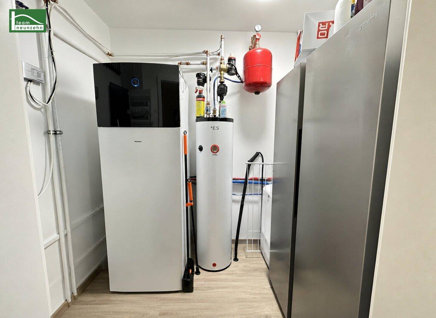 Technikraum mit moderner Wärmepumpe und Warmwasserspeicher für effiziente Energieversorgung.