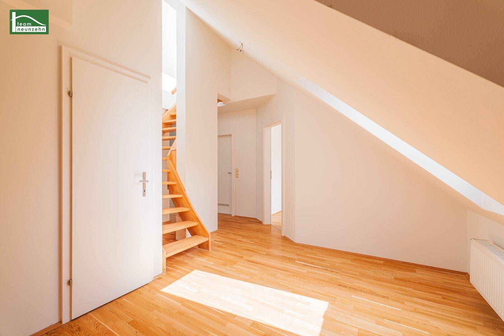 Heller Flurbereich im Dachgeschoss mit Holztreppe, die in das obere Stockwerk führt.