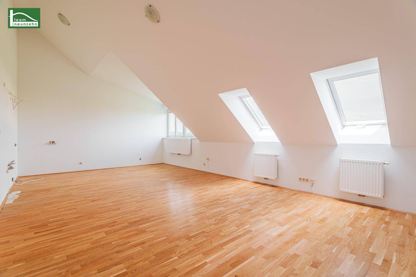Geräumiger Dachgeschossraum mit Holzboden, mehreren Dachfenstern und heller Atmosphäre.