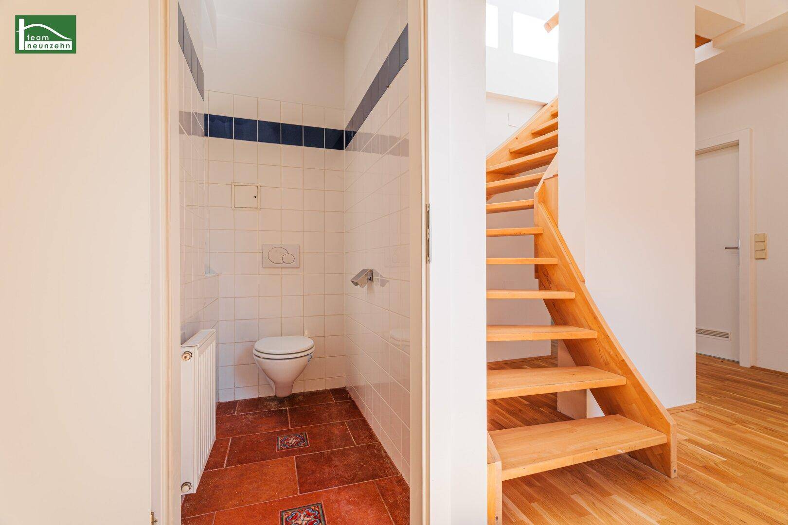 Separates WC mit Fliesenboden, Wand-WC und Heizkörper, praktisch neben der Holztreppe gelegen.