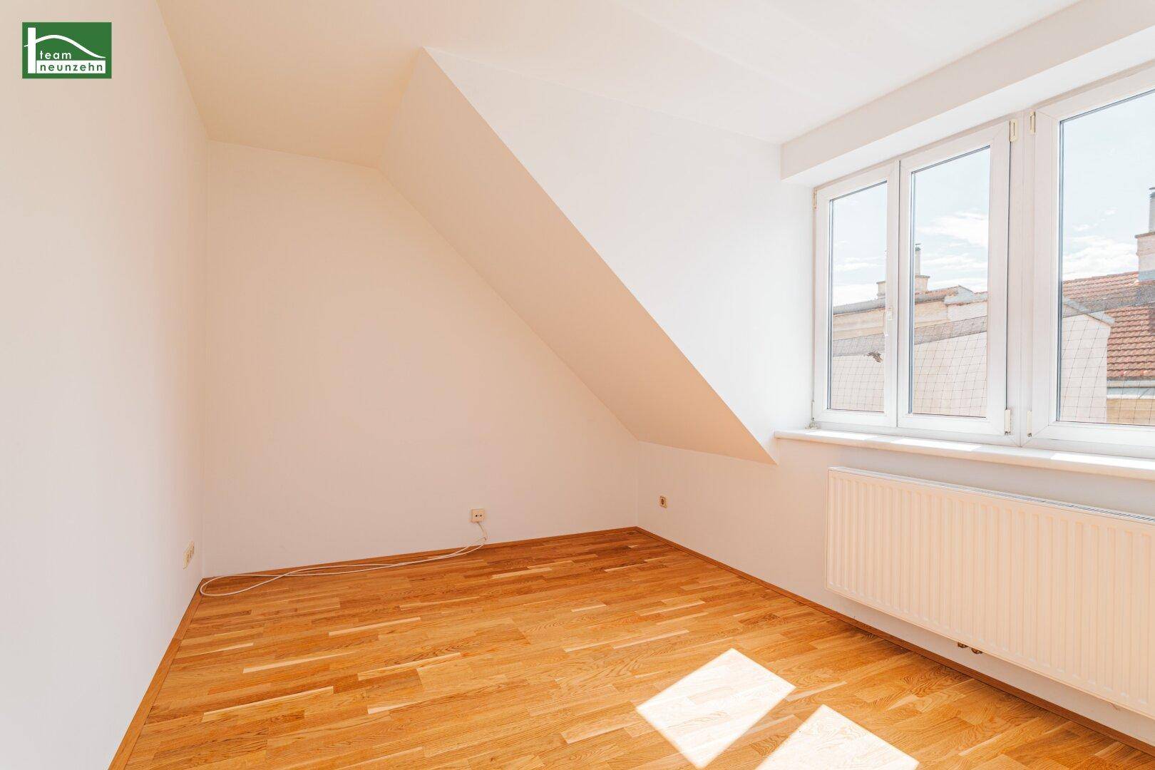 Gemütliches Zimmer im Dachgeschoss mit Holzboden, großem Fenster und Heizkörper, ideal als Schlaf- oder Arbeitszimmer.